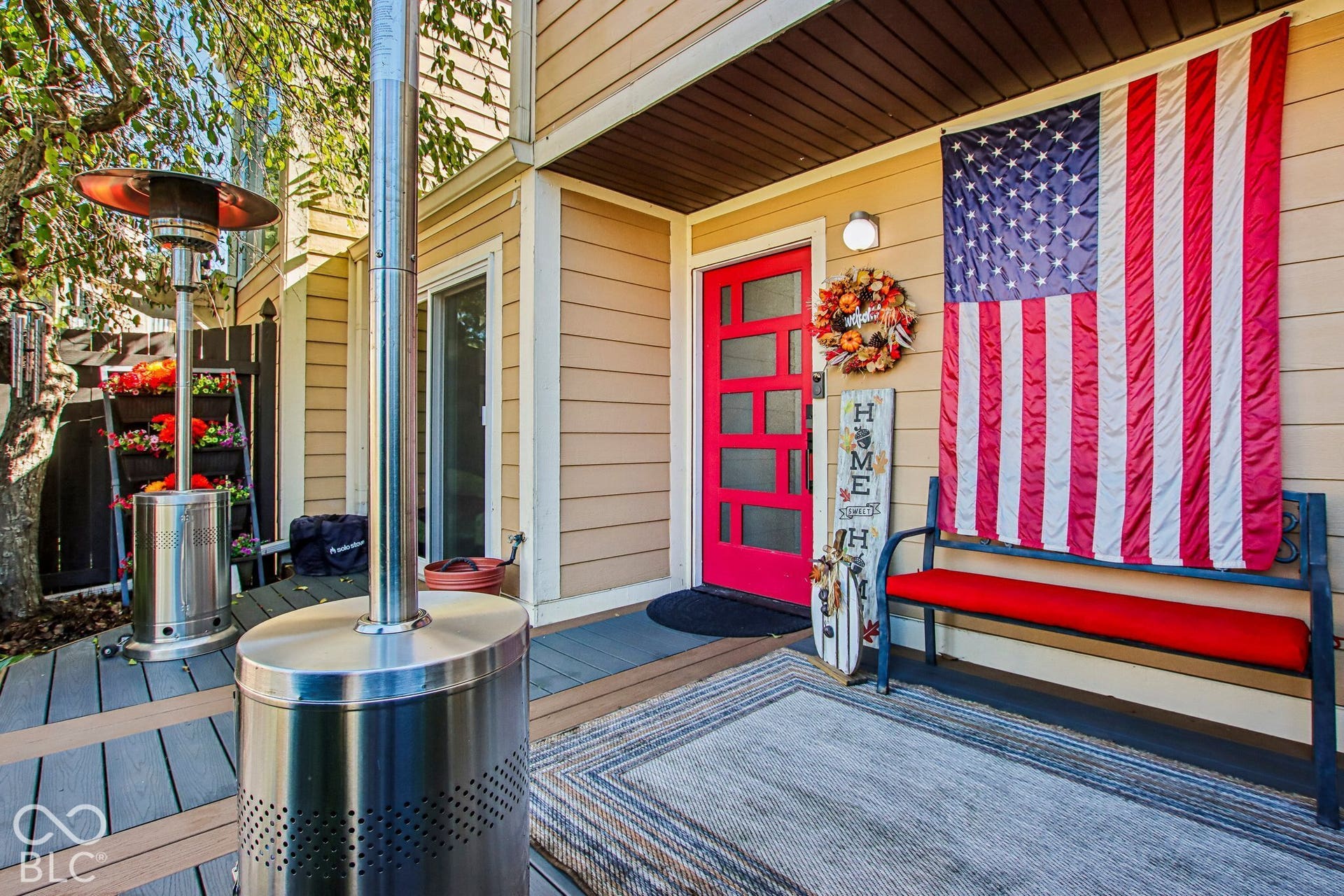 Exterior siding, red entry door with glass inserts, covered entry, and wood-look decking