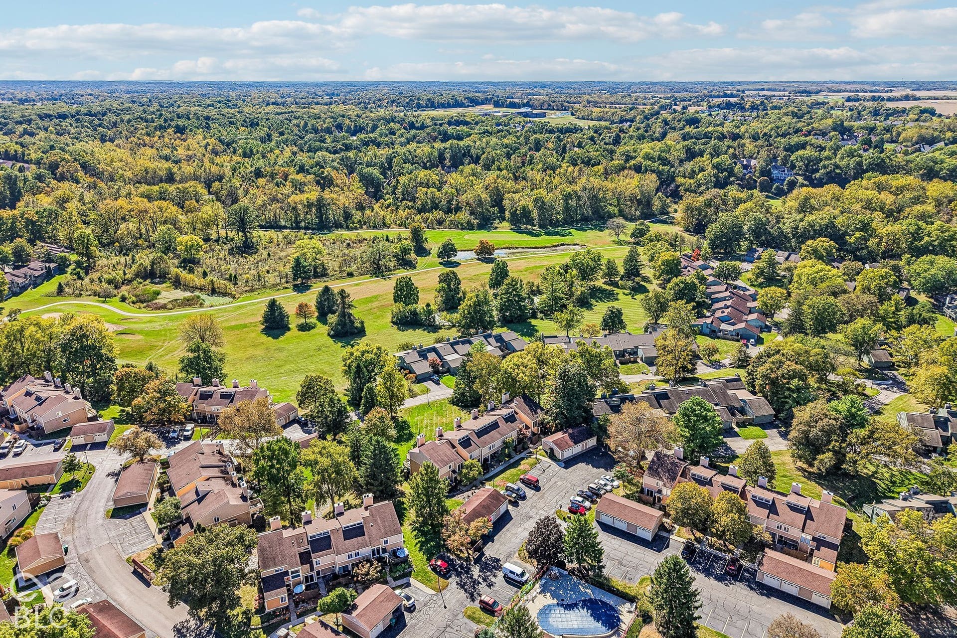 Aerial perspective showcasing a residential community with abundant mature trees and a golf course