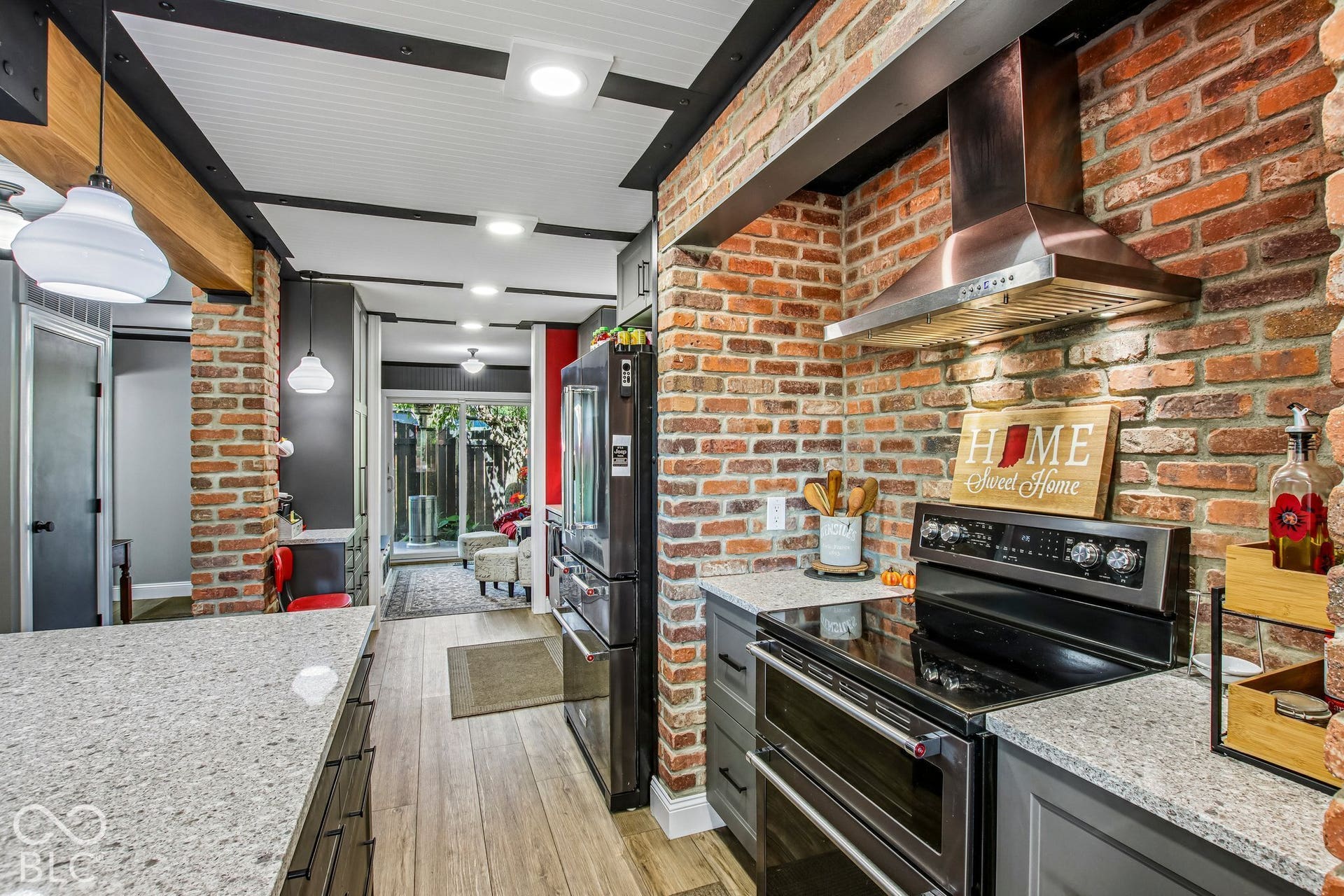 Kitchen featuring exposed brick accents, wood-finish flooring, recessed lighting, and stainless steel appliances