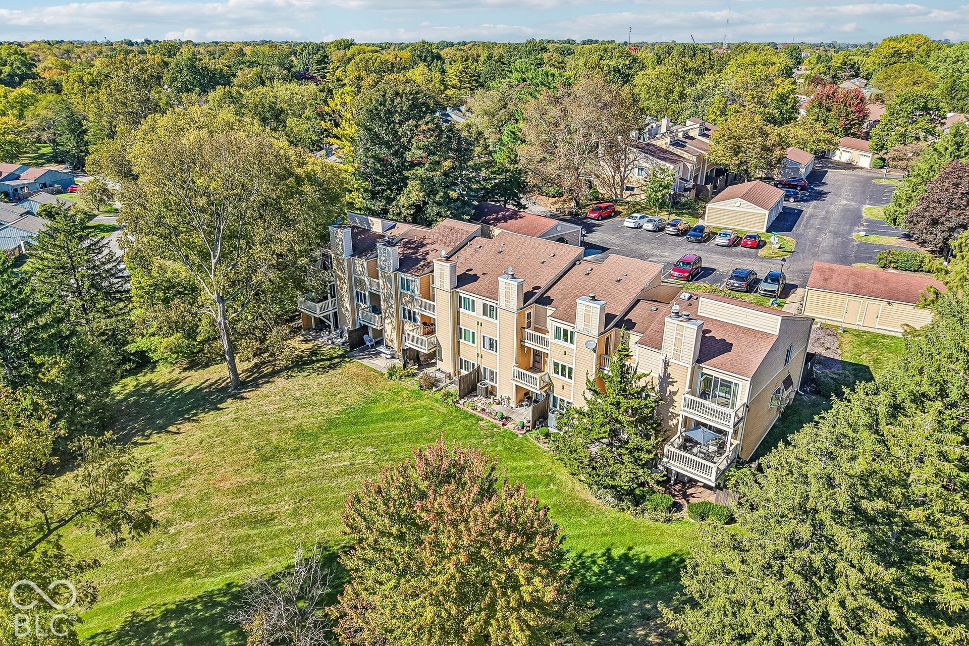 Multi-level residential structures with private balconies, surrounded by mature trees and landscaped grounds