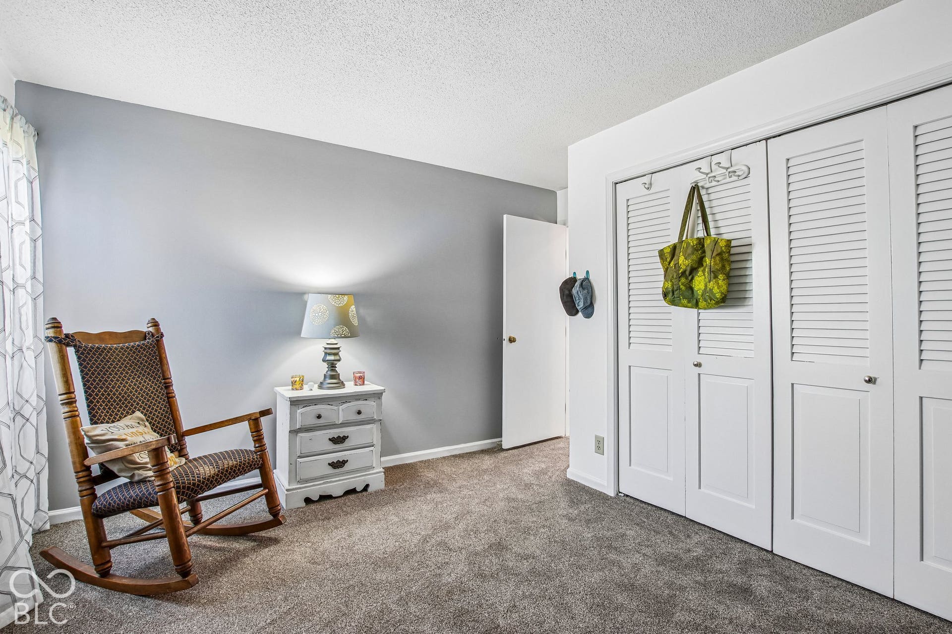Plush carpet flooring, white louvered closet doors, and neutral wall tones