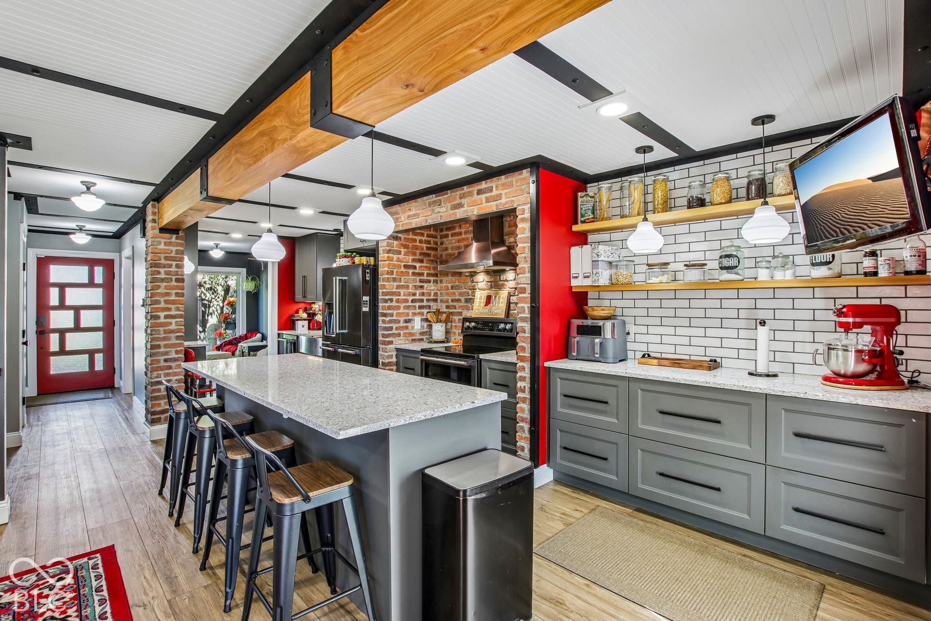 Kitchen featuring wood-finish flooring, a kitchen island with seating, a subway tile backsplash, open shelving, and a brick accent wall