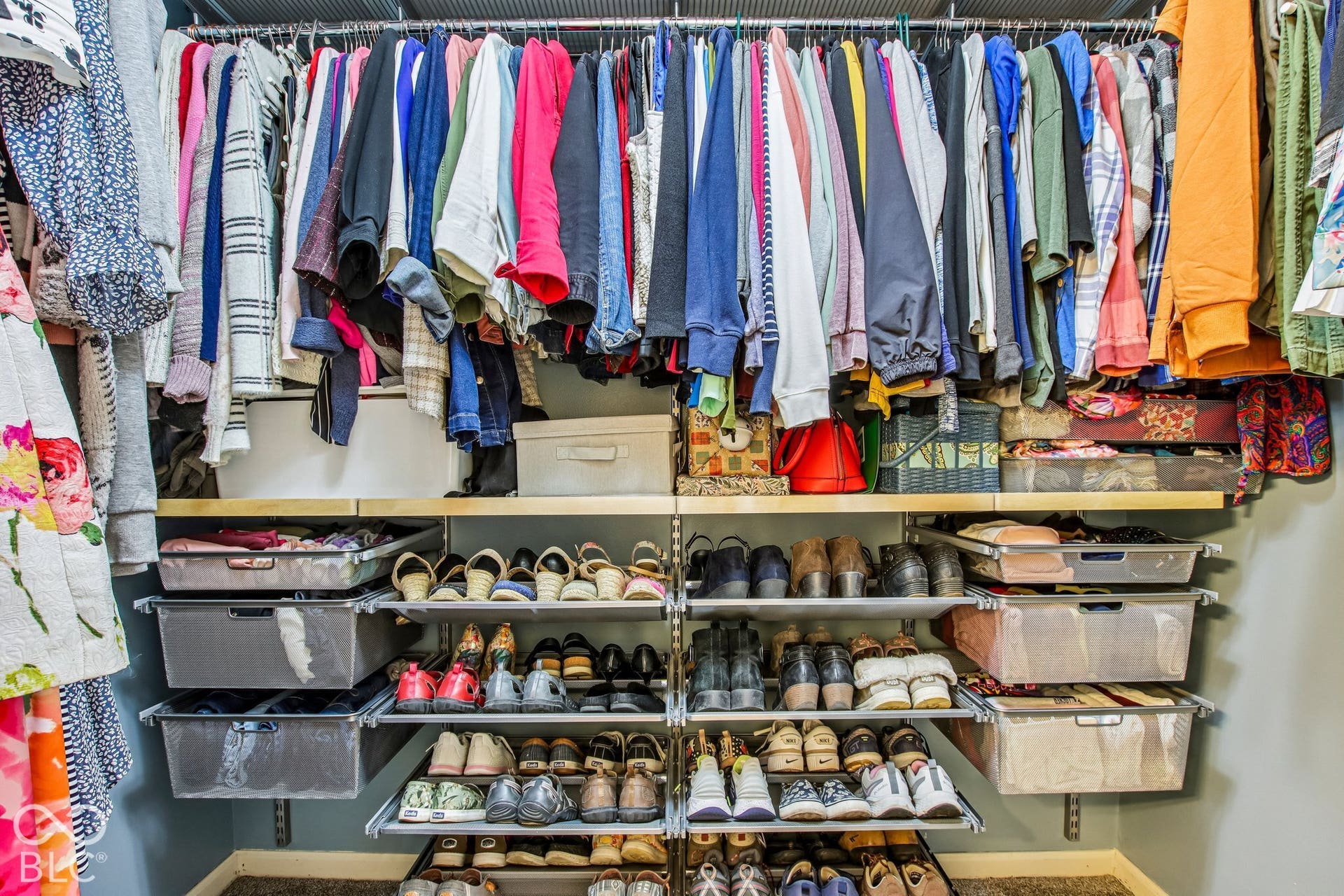 Custom closet system featuring multiple hanging rods, adjustable shelving, and pull-out storage bins