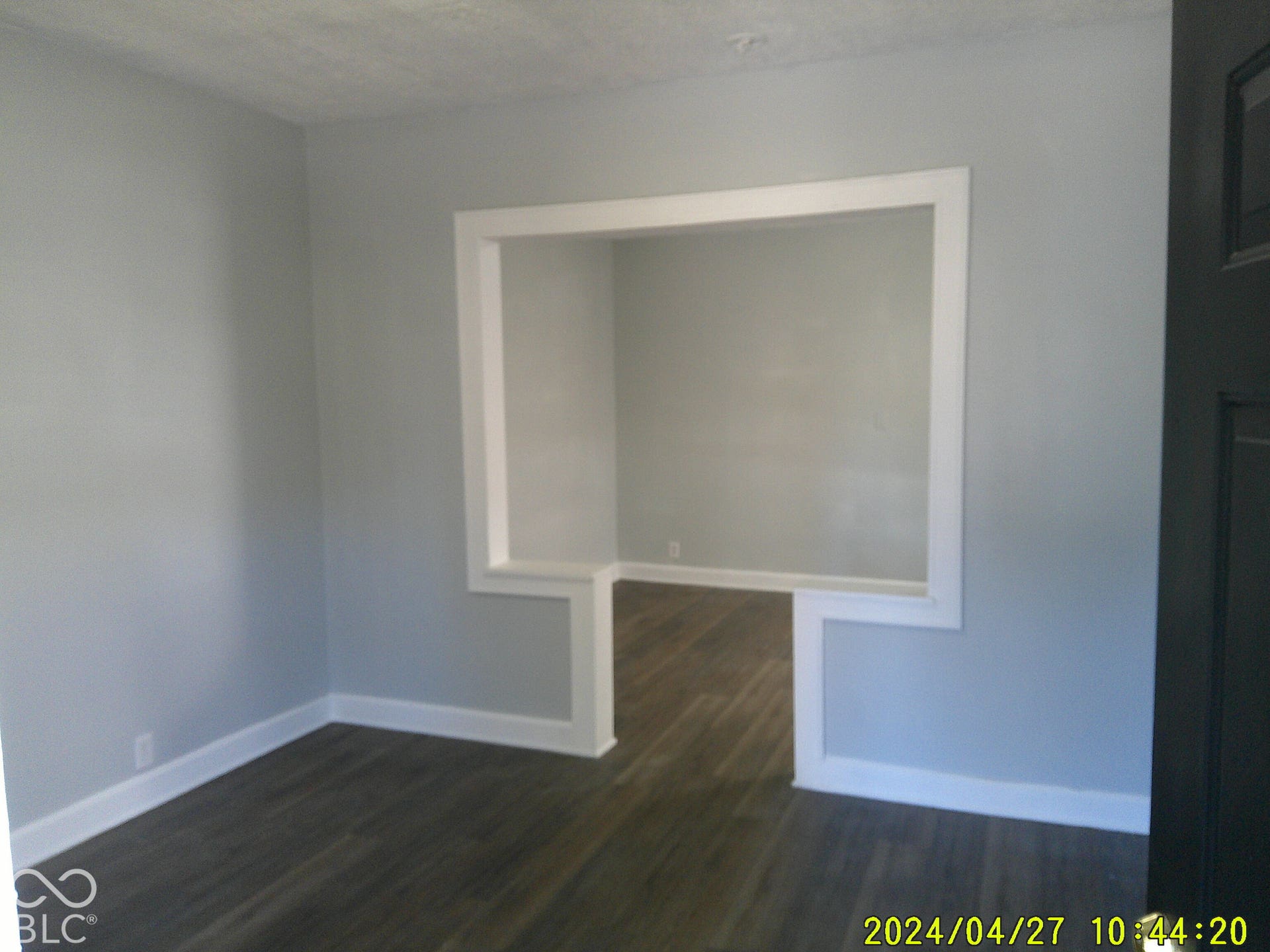 Wood-finish flooring throughout, framed opening to an additional room, and light-toned wall finishes