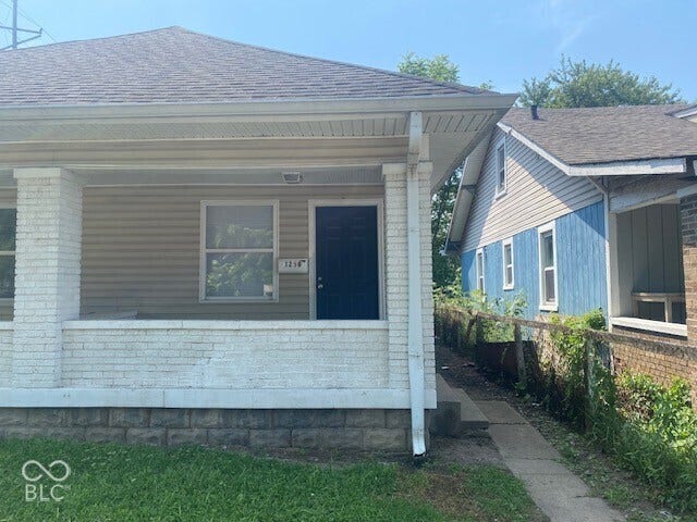Front exterior with a covered porch featuring white brick columns and siding