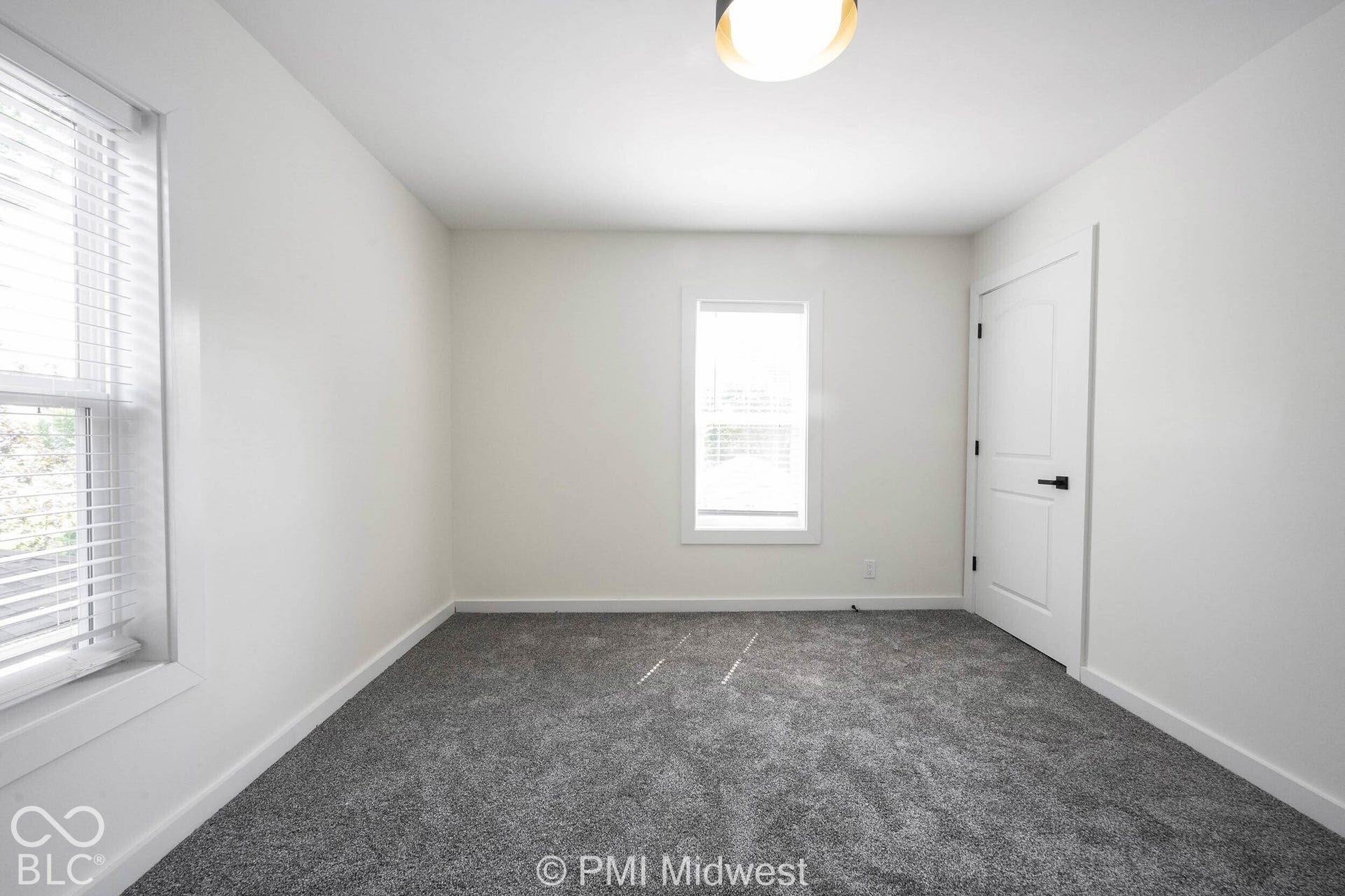 Neutral-toned interior with gray textured carpeting, white walls, and a modern ceiling-mounted light fixture
