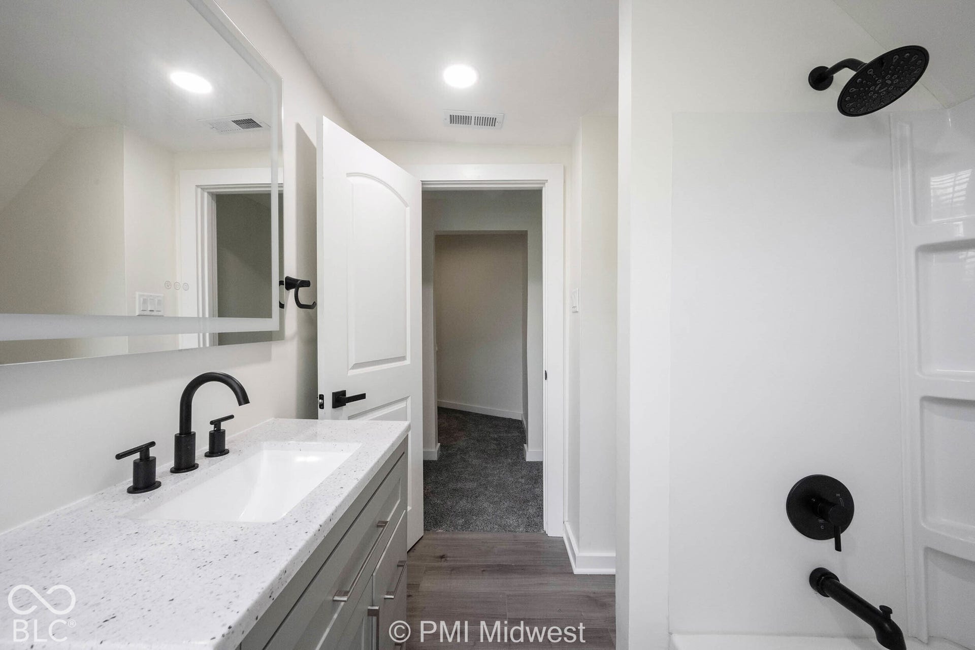 Vanity with white integrated sink, speckled countertop, and matte black faucet
