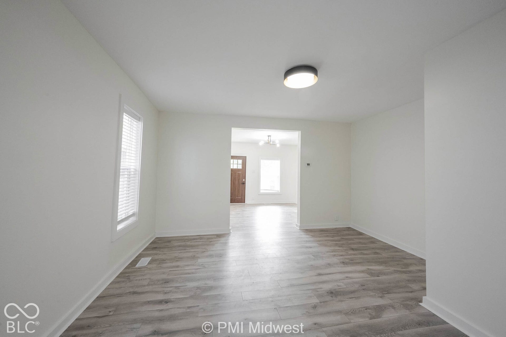 Wood-finish flooring throughout, bright white walls, and a recessed ceiling light