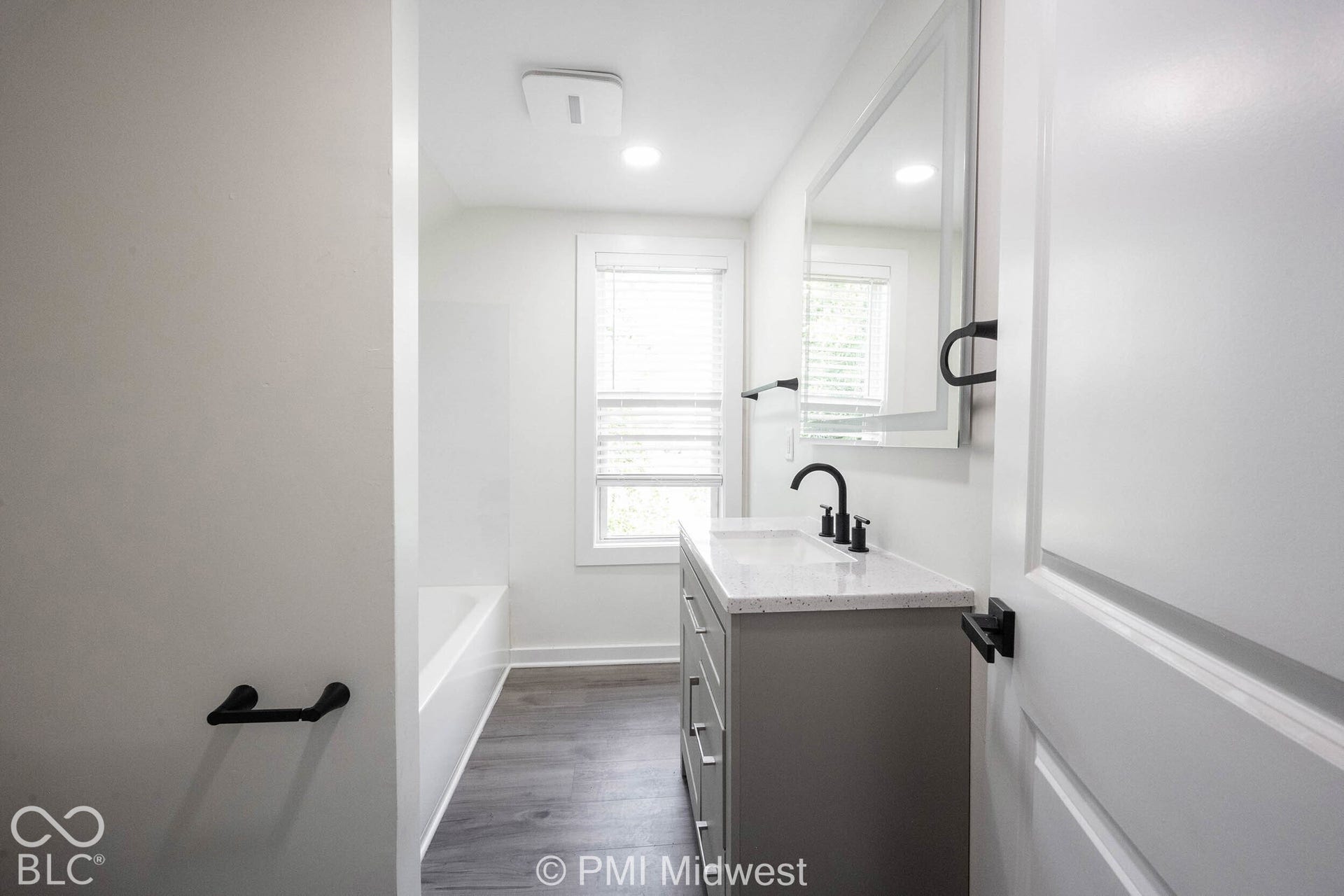 Bathroom featuring a single vanity with stone-finish countertop, undermount sink, and matte black faucet