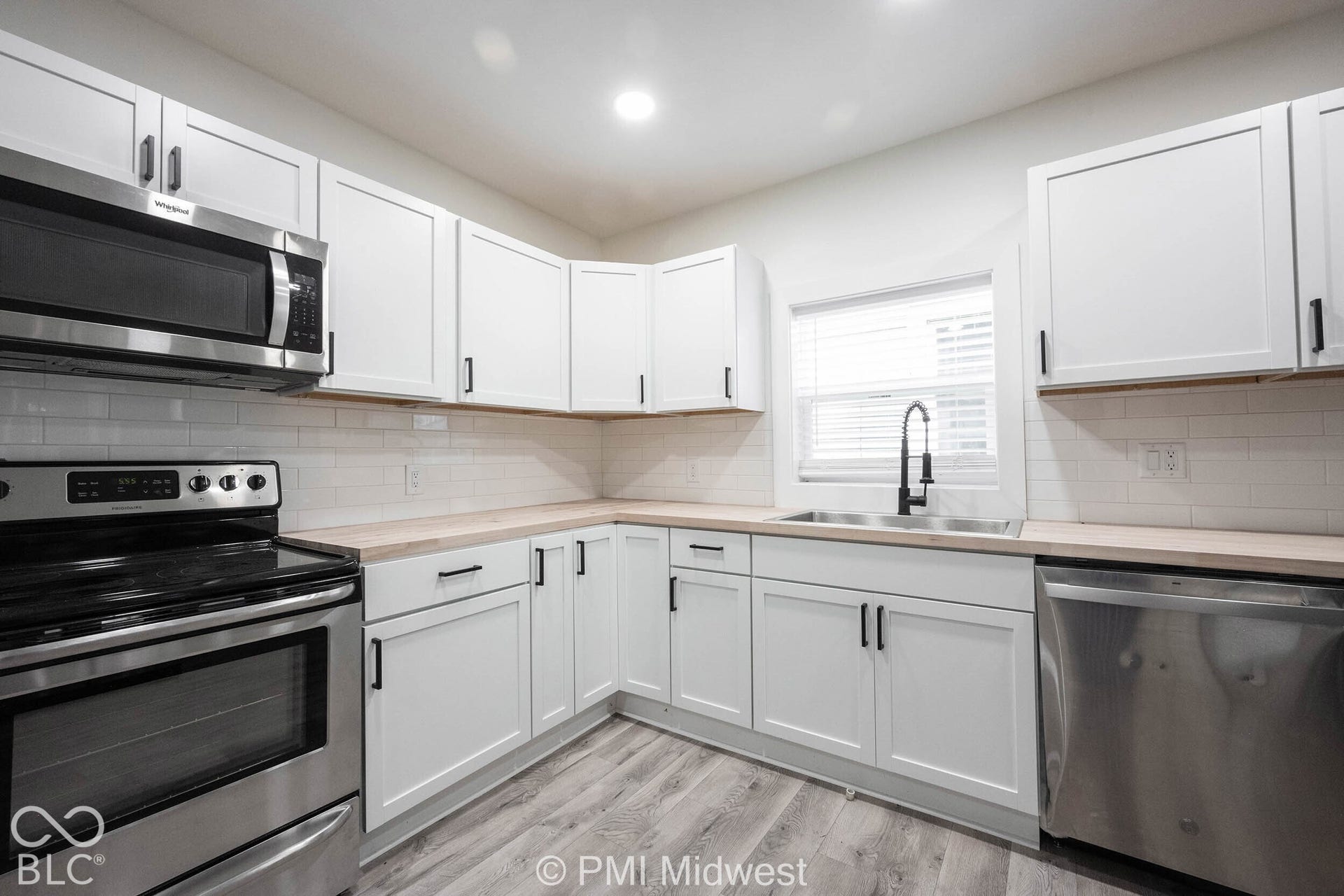 Kitchen featuring white cabinetry, stainless steel appliances, wood-finish countertops, white subway tile backsplash, and wood-look flooring