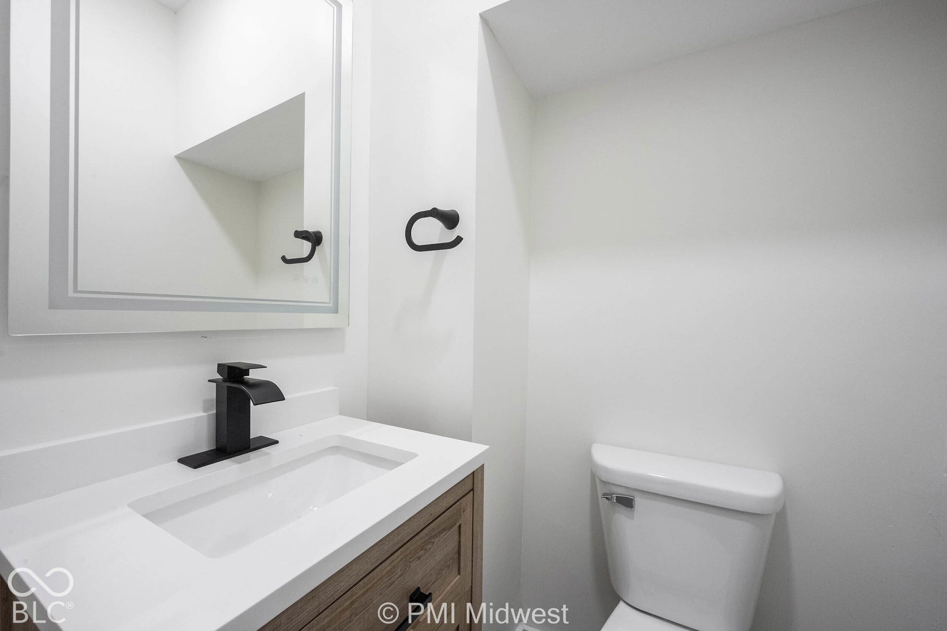 Integrated vanity with a rectangular sink, matte black waterfall faucet, and wood-finish cabinetry