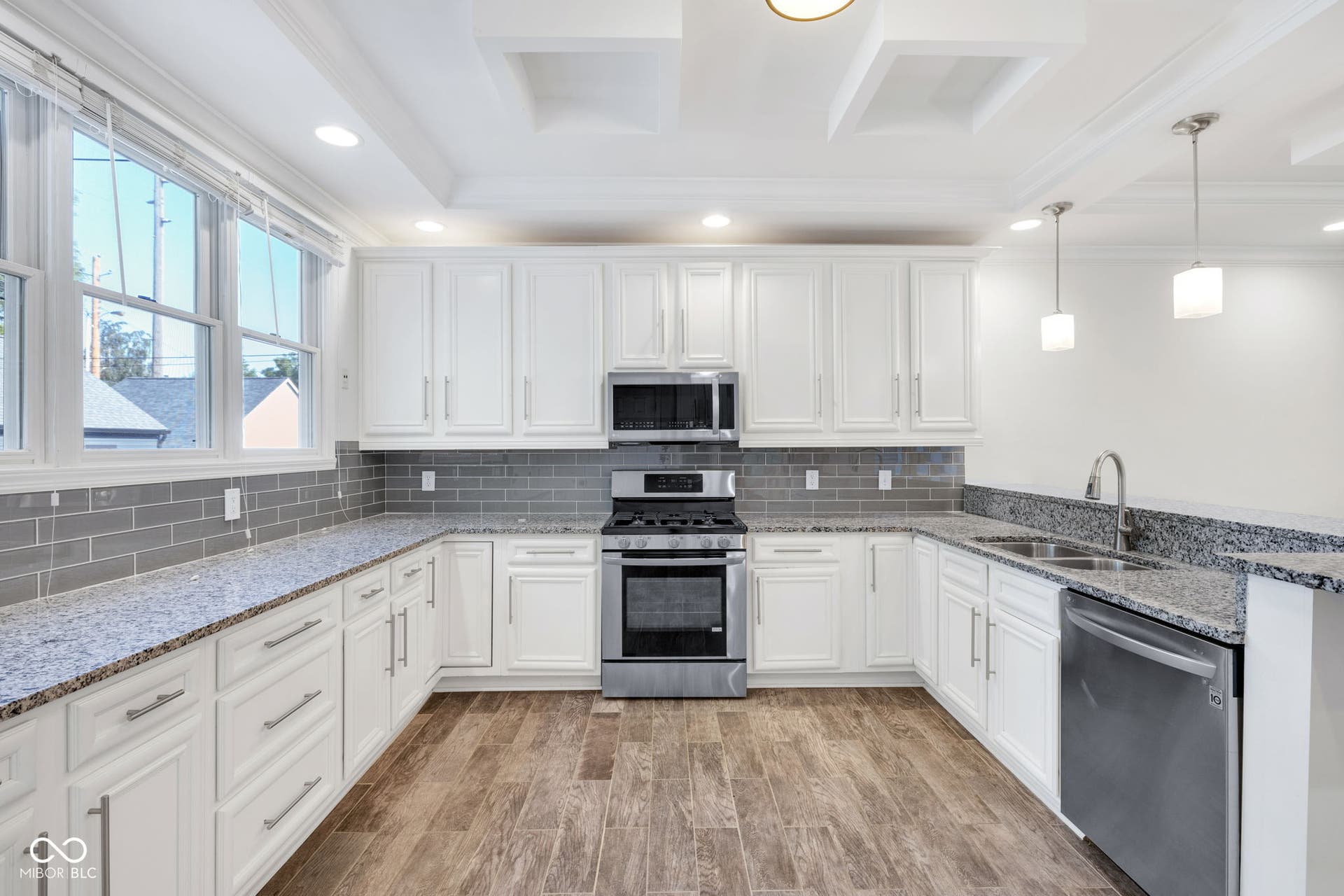 kitchen with ornamental molding, stainless steel appliances, tasteful backsplash, white cabinetry, and a peninsula