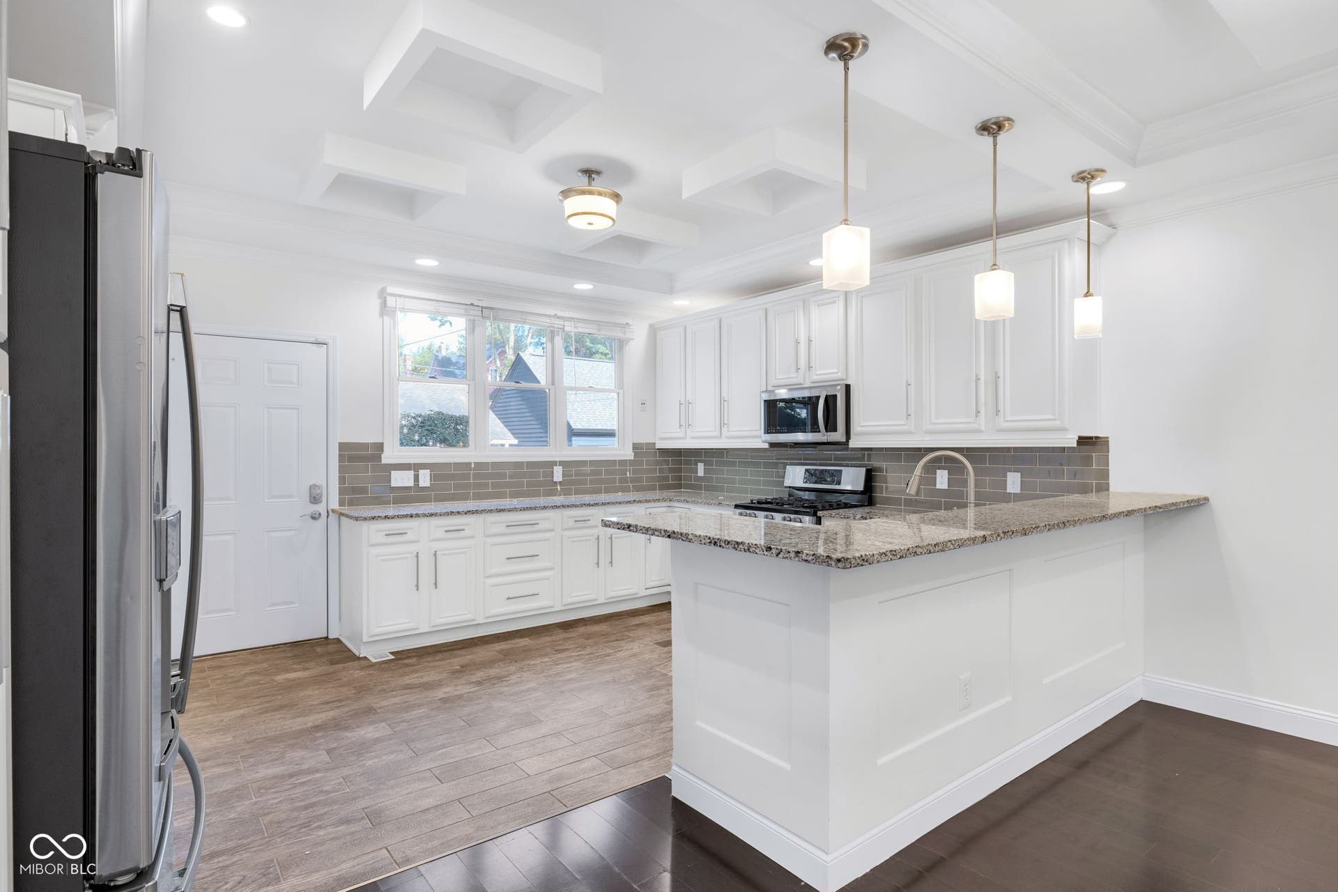 Kitchen & dining area - freshly painted (7/2025) featuring hardwood floors, ample cabinet space, stone countertops and stainless appliances.