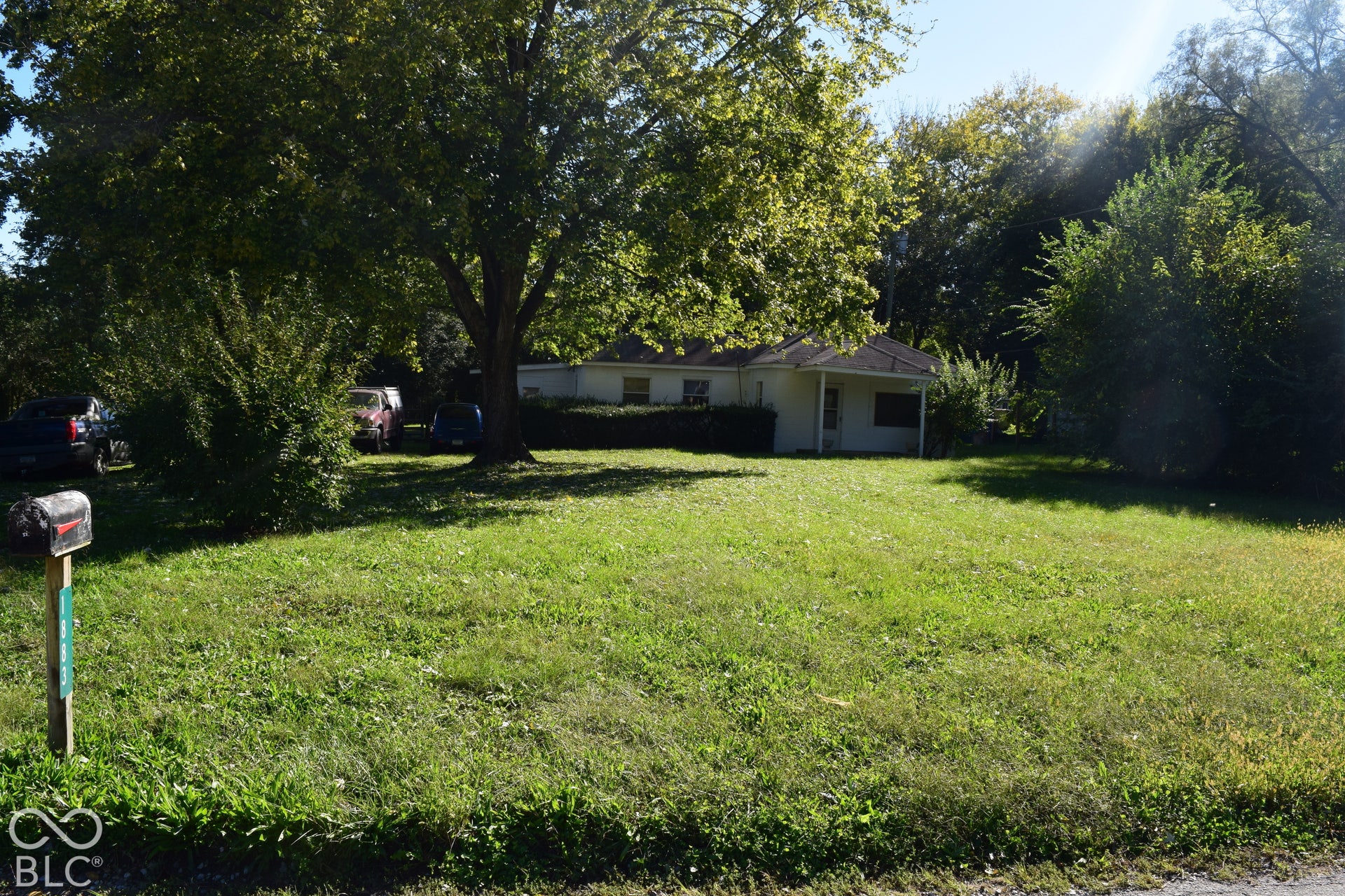 Expansive grassy lawn with mature trees and a single-story residence