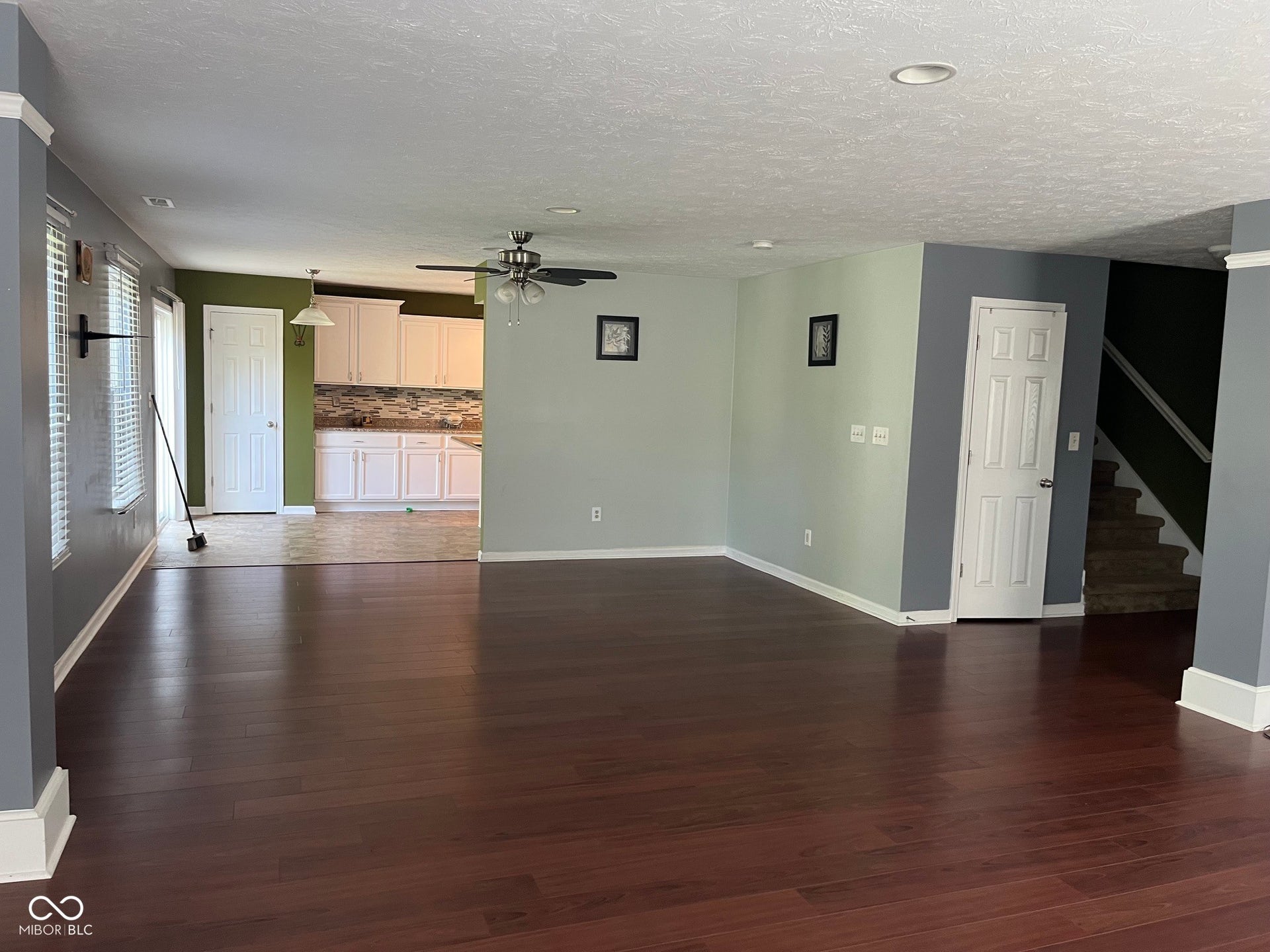 Expansive living area with wood-finish flooring, recessed lighting, and a ceiling fan