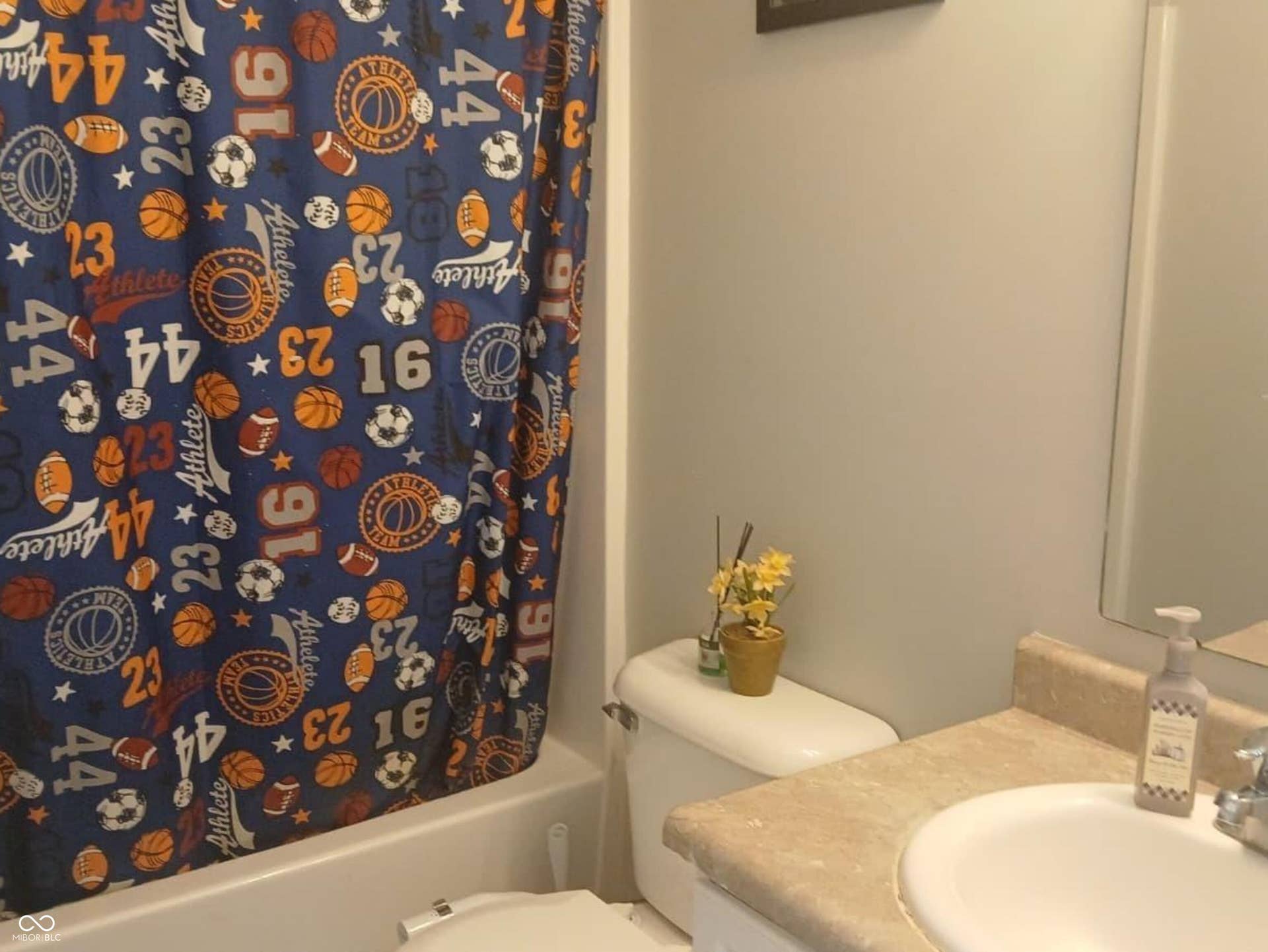 Bathroom featuring a white tub, toilet, and a vanity with an integrated sink and mirror