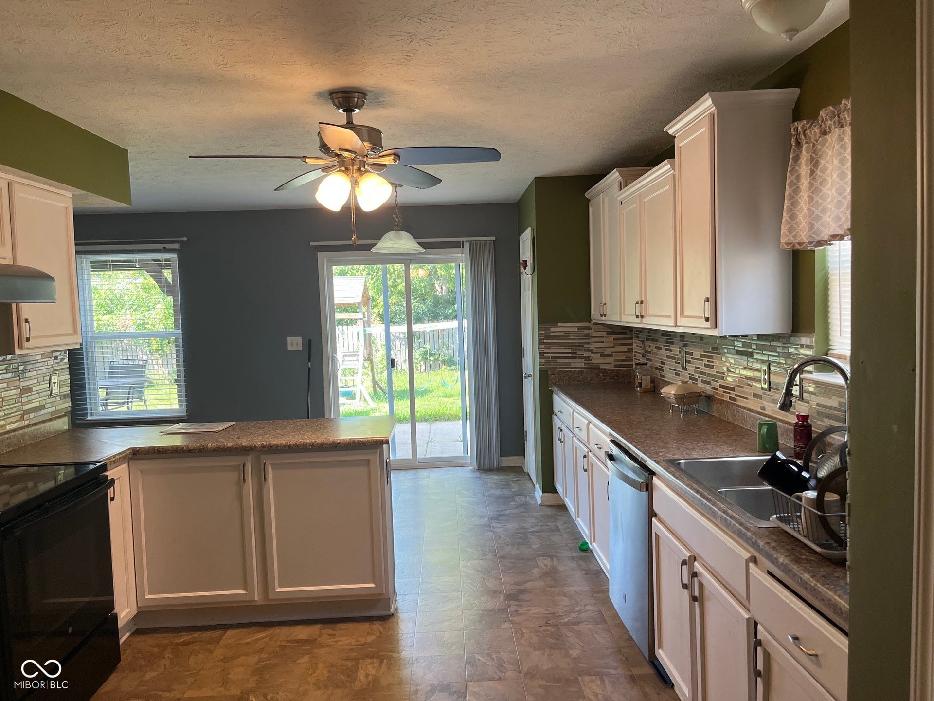 Kitchen featuring white cabinetry, stone-look countertops, and a full tile backsplash