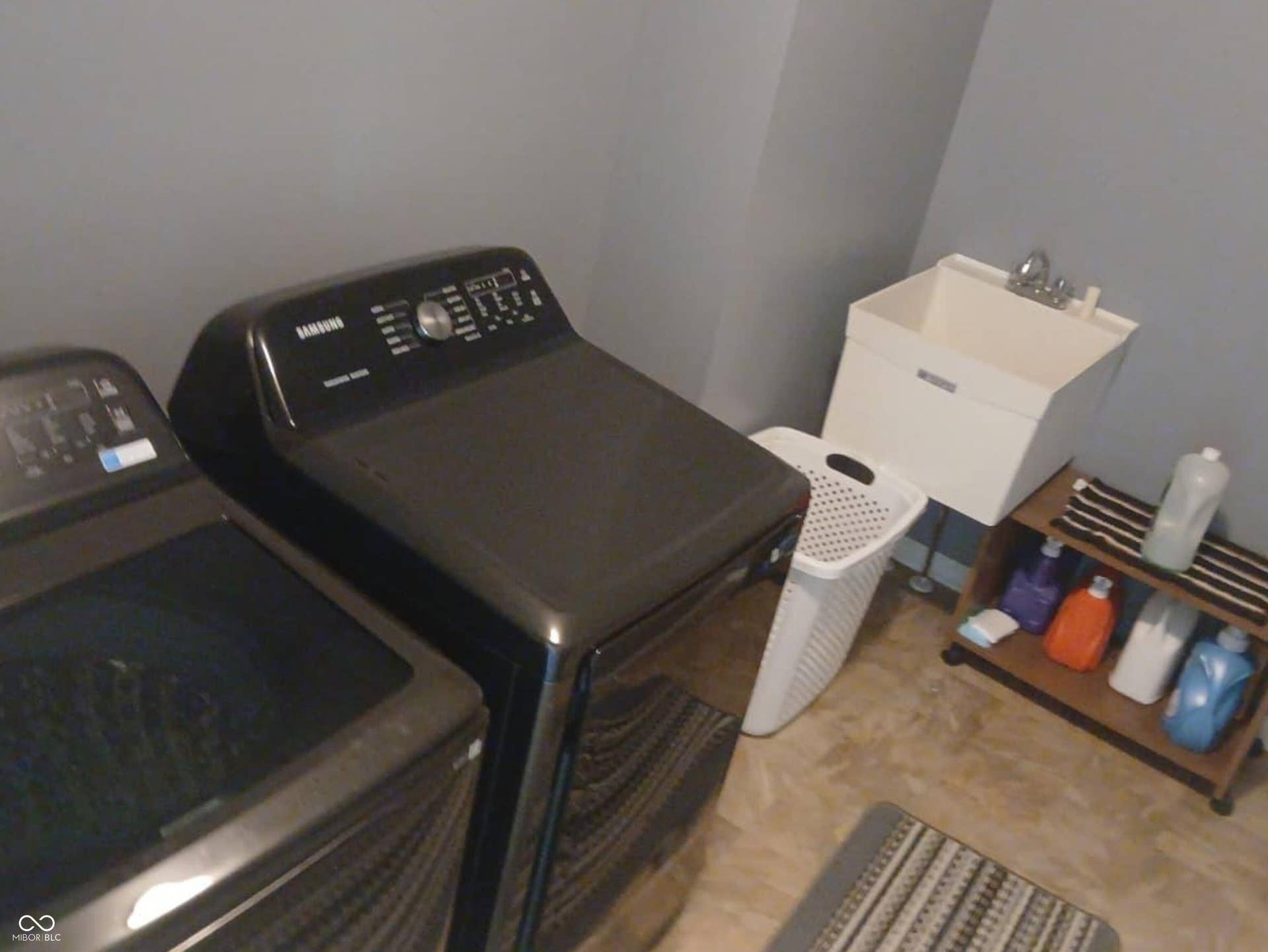 Utility sink with chrome faucet, light gray walls, and wood-finish flooring