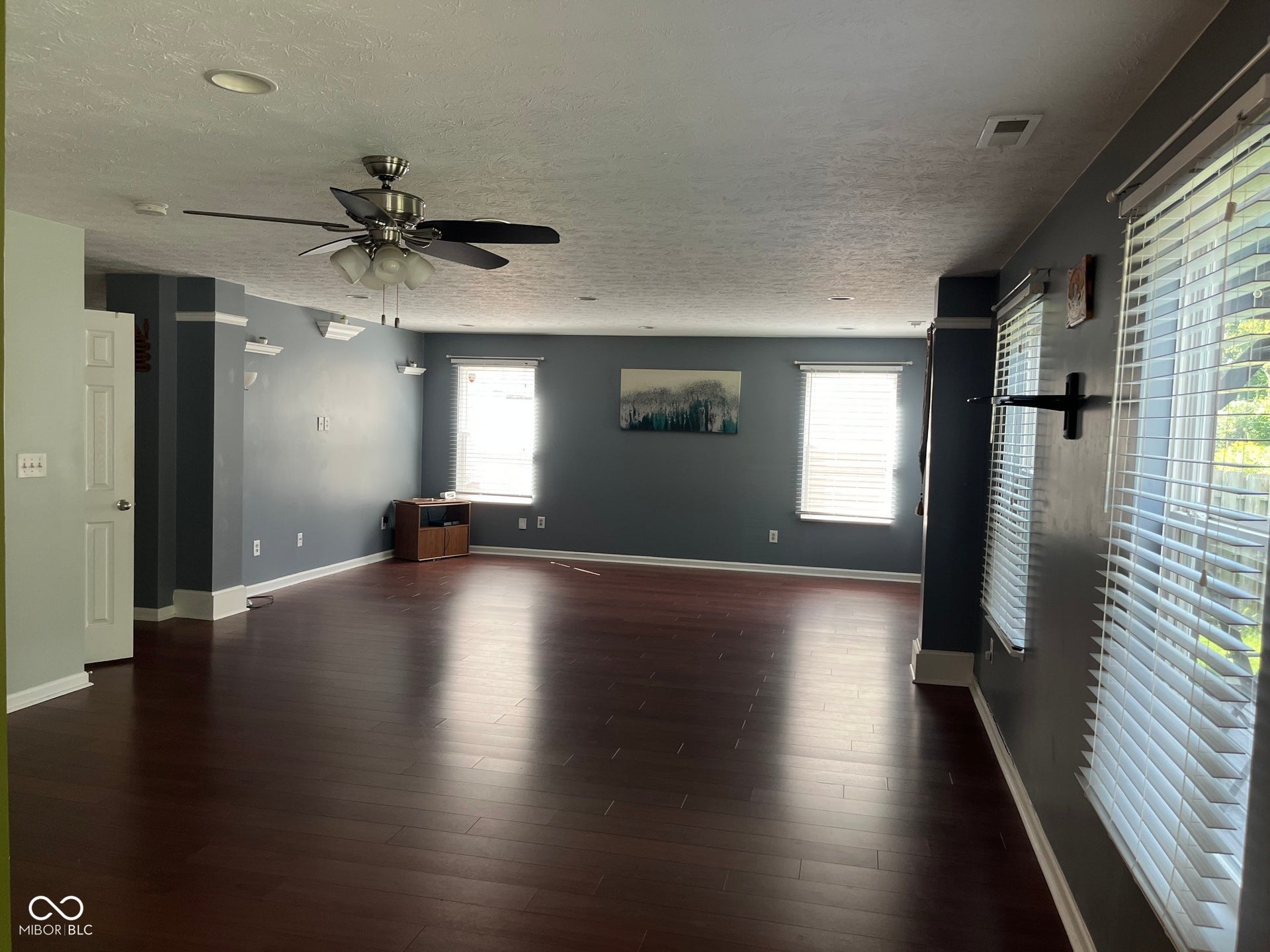 Expansive room featuring wood-finish flooring, recessed lighting, and multiple windows with blinds