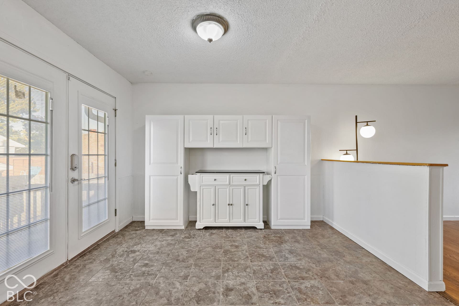 White built-in cabinetry, French doors, and ceiling-mounted light fixture