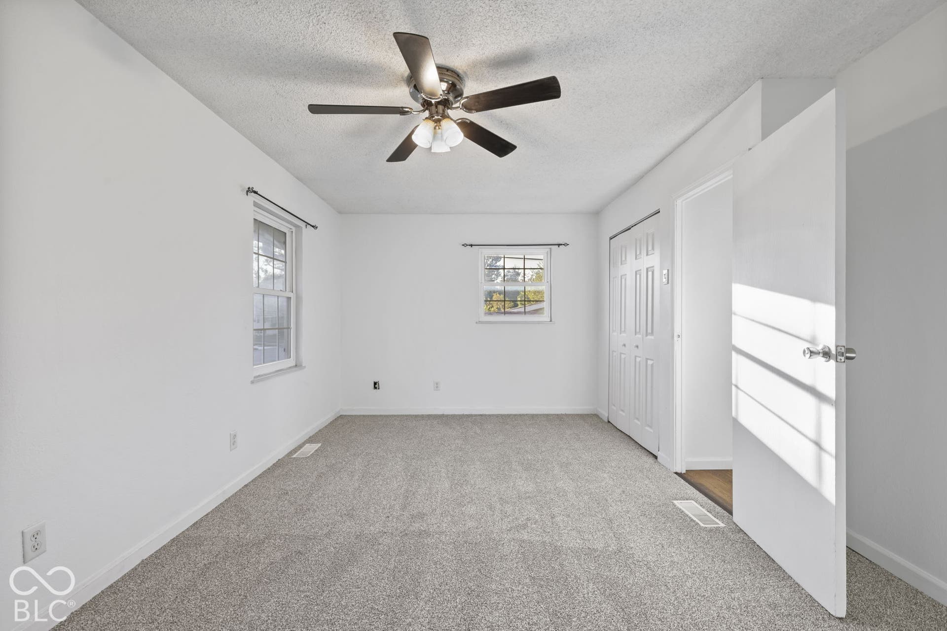 Gray carpet flooring, white walls, and a ceiling fan with light fixture