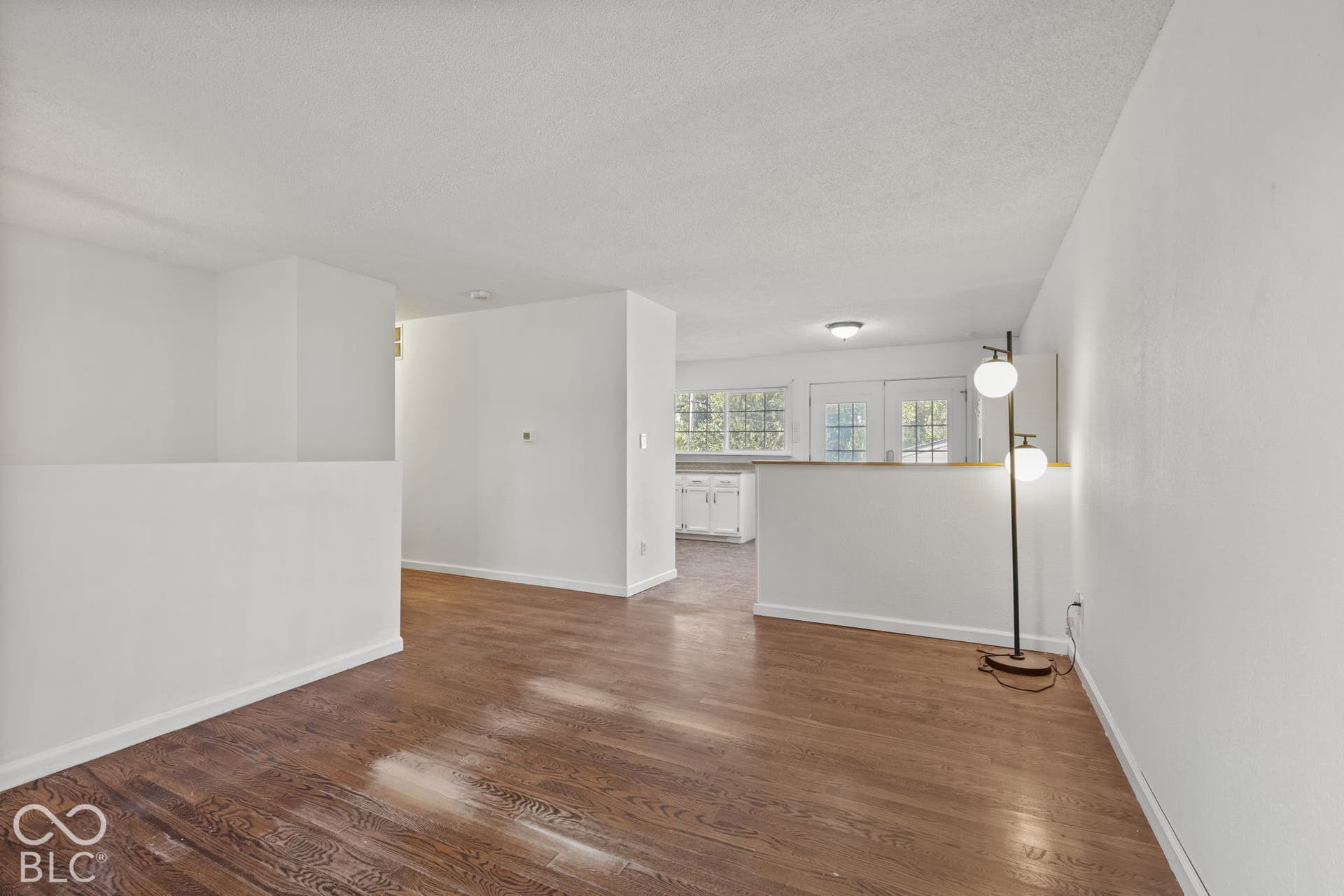 Hardwood-finish flooring, white walls, and a partial wall separating spaces