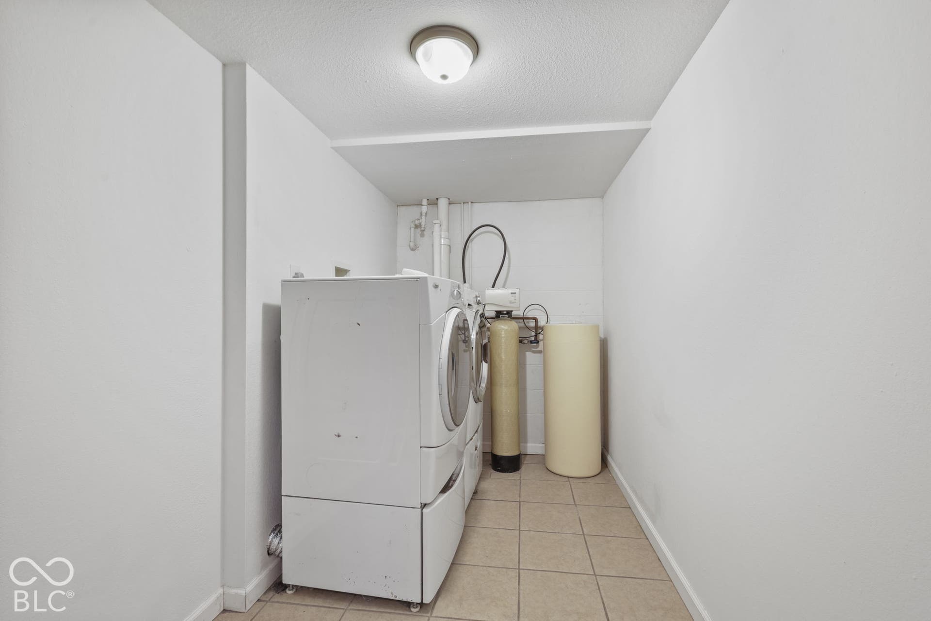 Utility area featuring a washer and dryer, tile flooring, and a flush-mount ceiling light