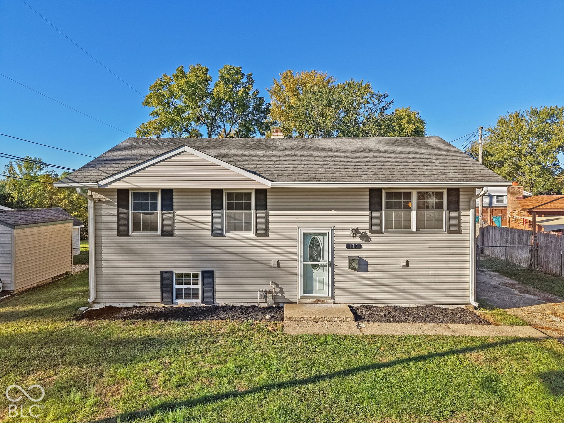 Exterior featuring light-toned siding, dark window shutters, a light blue entry door, and a shingled roof