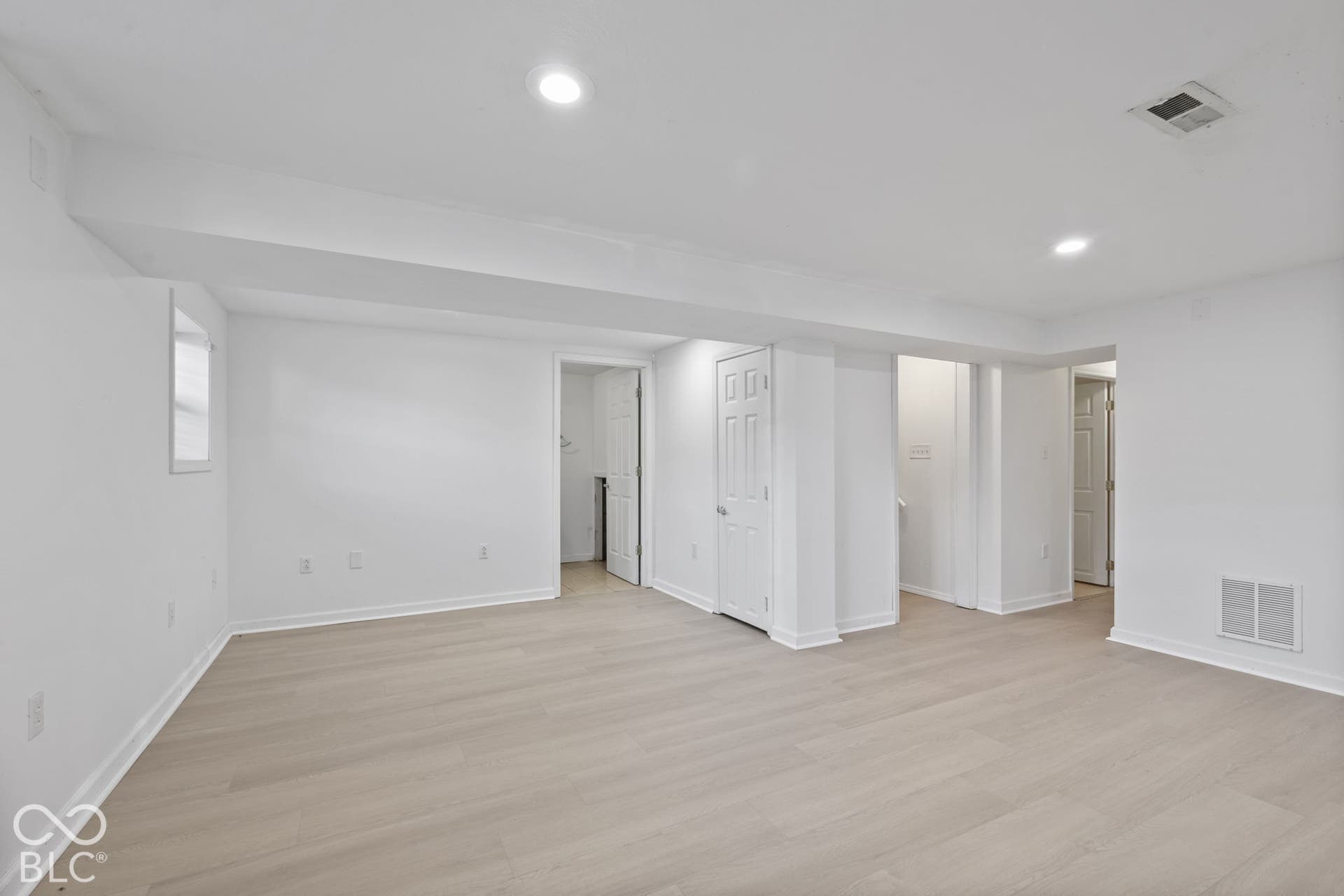 Expansive room featuring wood-finish flooring, recessed lighting, and multiple doorways