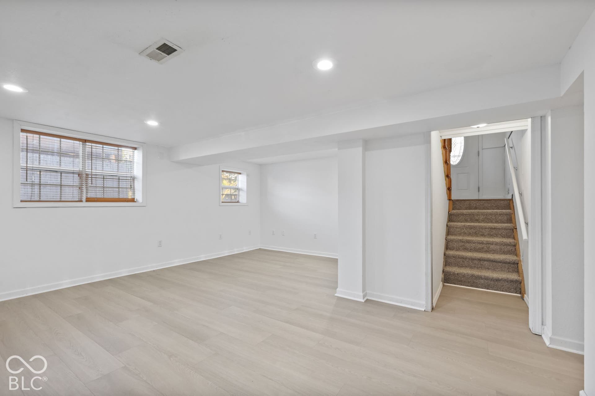 Spacious room with wood-finish flooring, recessed lighting, and bright white walls