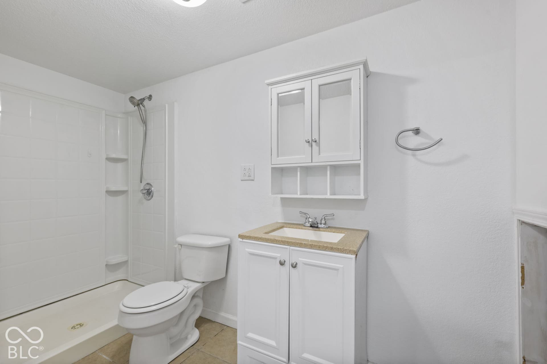 Bathroom featuring a white shower stall, white vanity with a light-colored countertop, and a wall-mounted medicine cabinet with glass-front doors