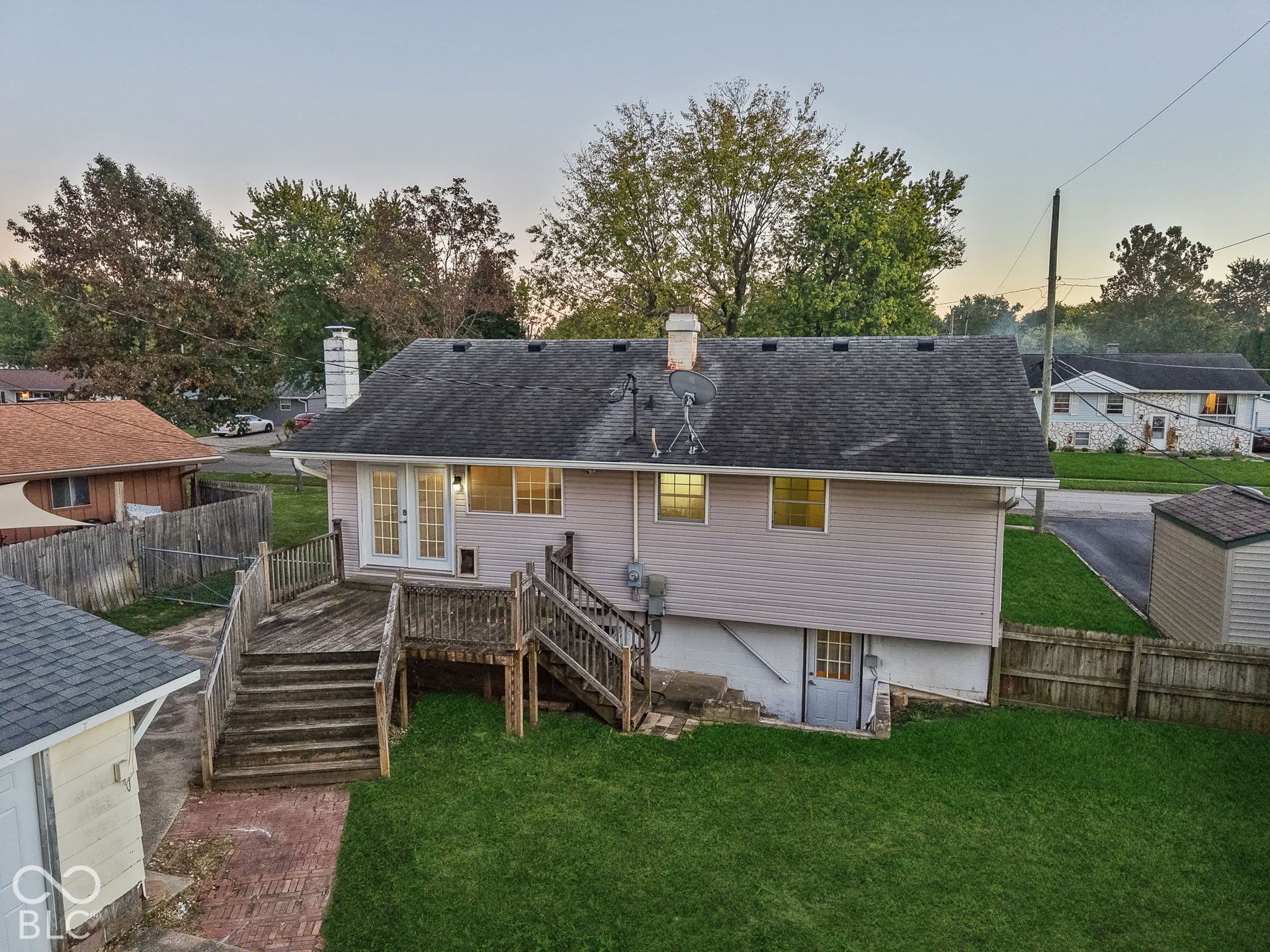Virtually Altered - Expansive backyard featuring a manicured lawn, a multi-level wood deck, a wood privacy fence, and a storage shed