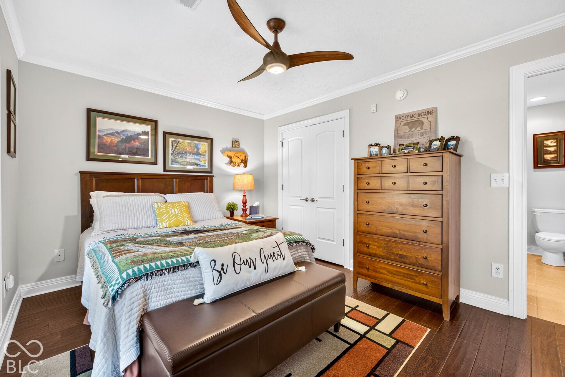 Bedroom featuring wood-finish flooring, a ceiling fan, crown molding, and a white paneled door