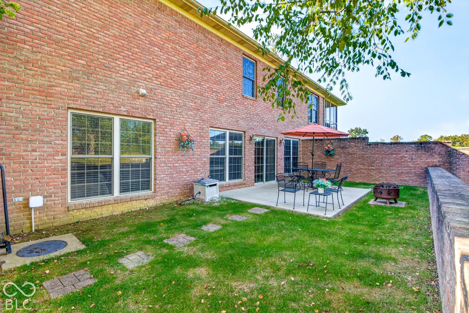 Brick exterior featuring multiple windows and a concrete patio