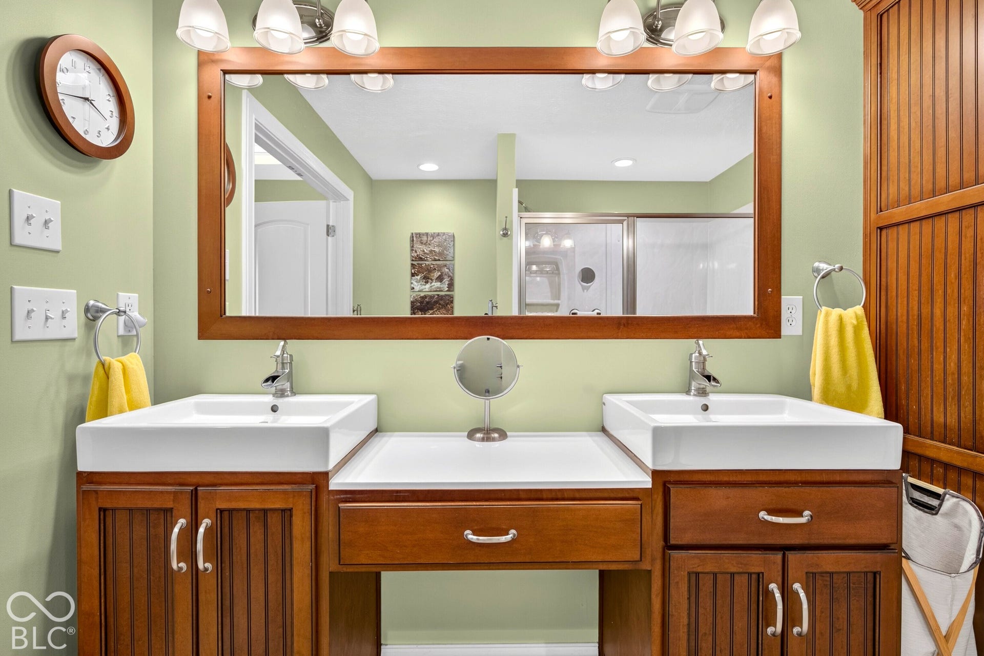 Dual rectangular vessel sinks, extensive wood cabinetry, and a full-width framed mirror with overhead lighting