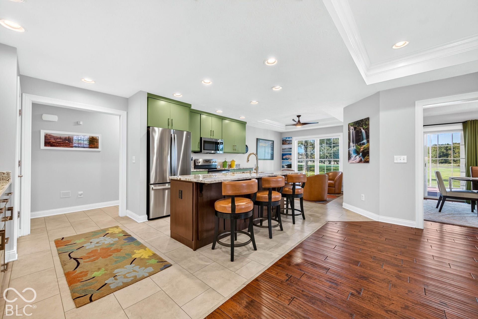 Kitchen featuring green upper cabinetry, stainless steel appliances, and a central island with bar seating