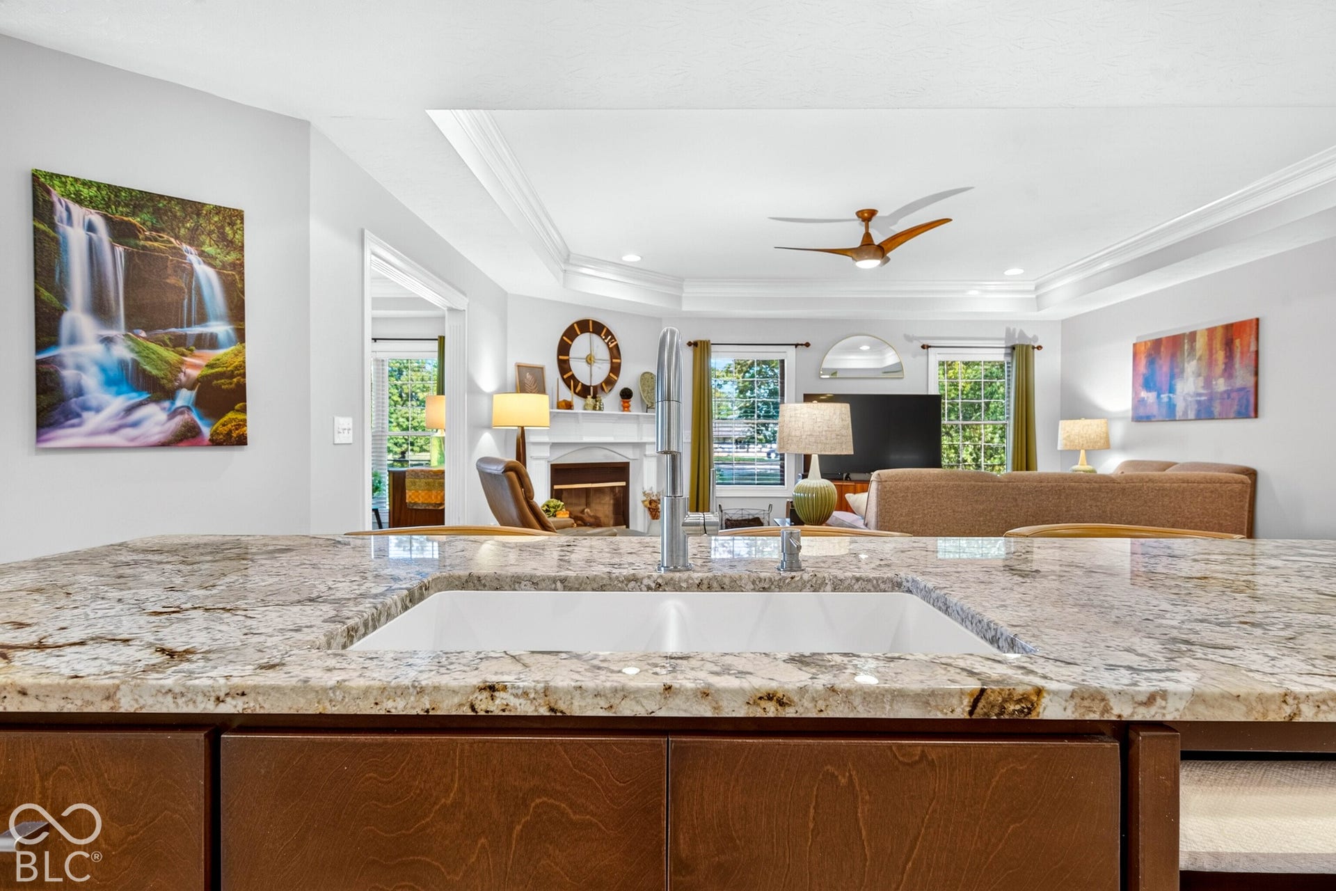 Undermount sink with a gooseneck faucet, wood-finish cabinetry, and a light-toned countertop
