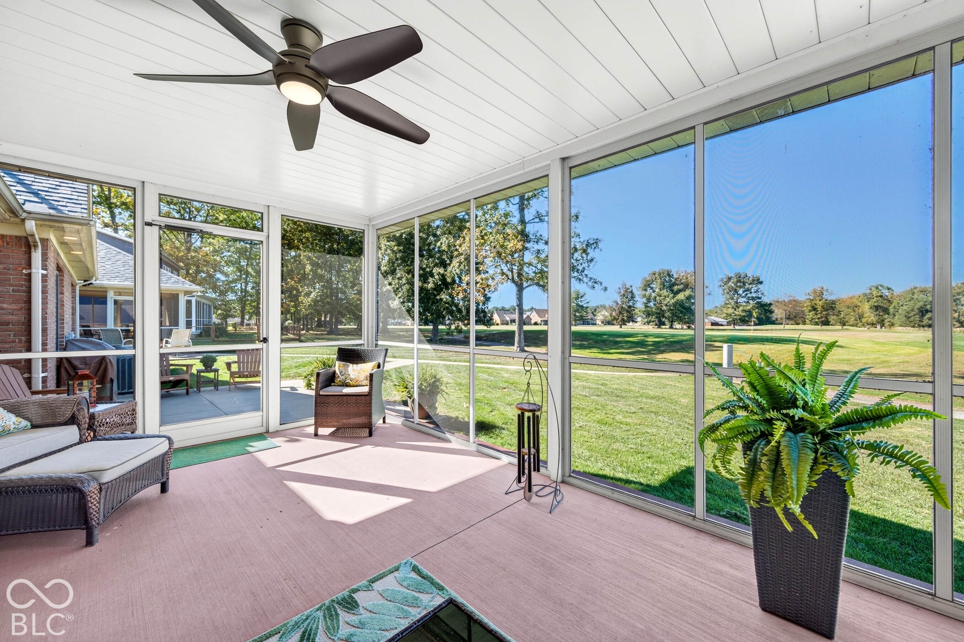 Screened-in porch featuring a ceiling fan with integrated lighting, a light pink concrete floor, and multiple screened panels