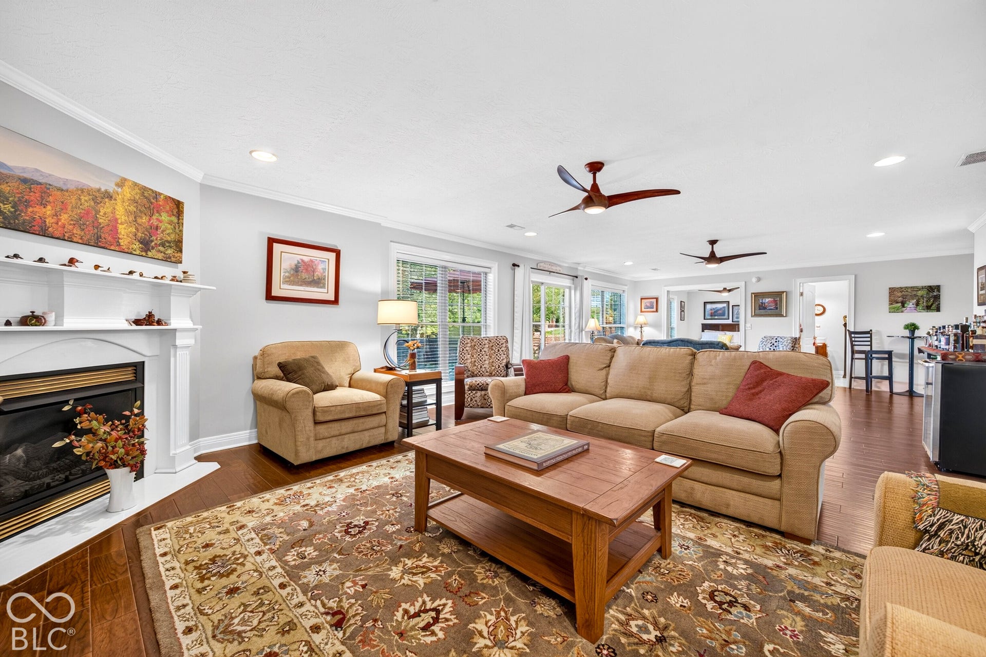 Spacious living area featuring wood-finish flooring, a white mantel fireplace, and recessed lighting