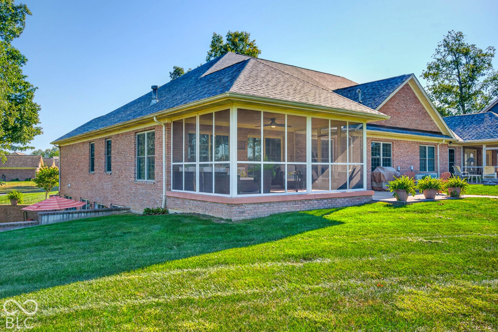 Brick exterior with multiple windows, screened porch, and a concrete patio