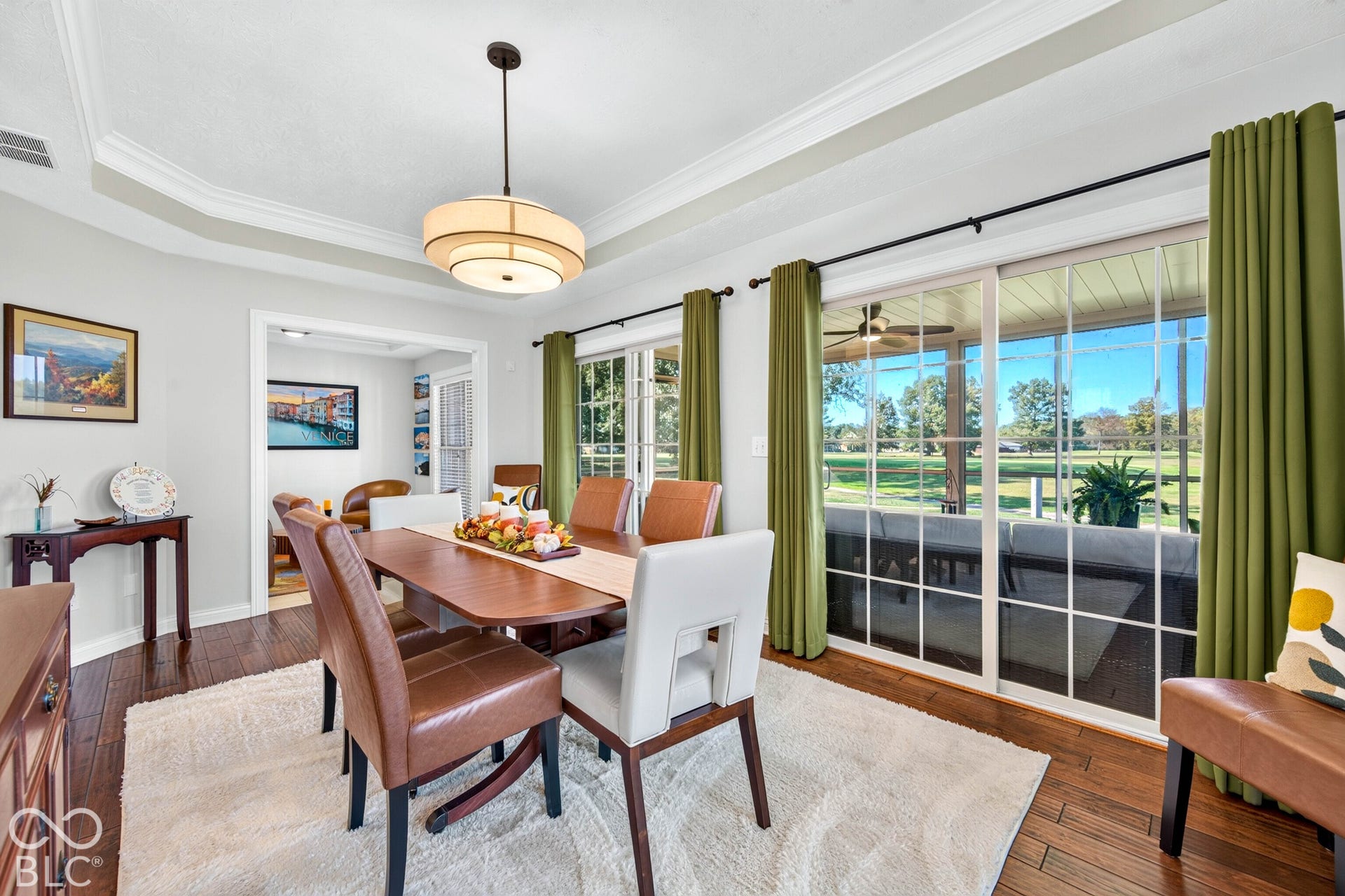 Tray ceiling with crown molding, wood-finish flooring, sliding glass doors, built-in overhead lighting, and an expansive screened-in porch