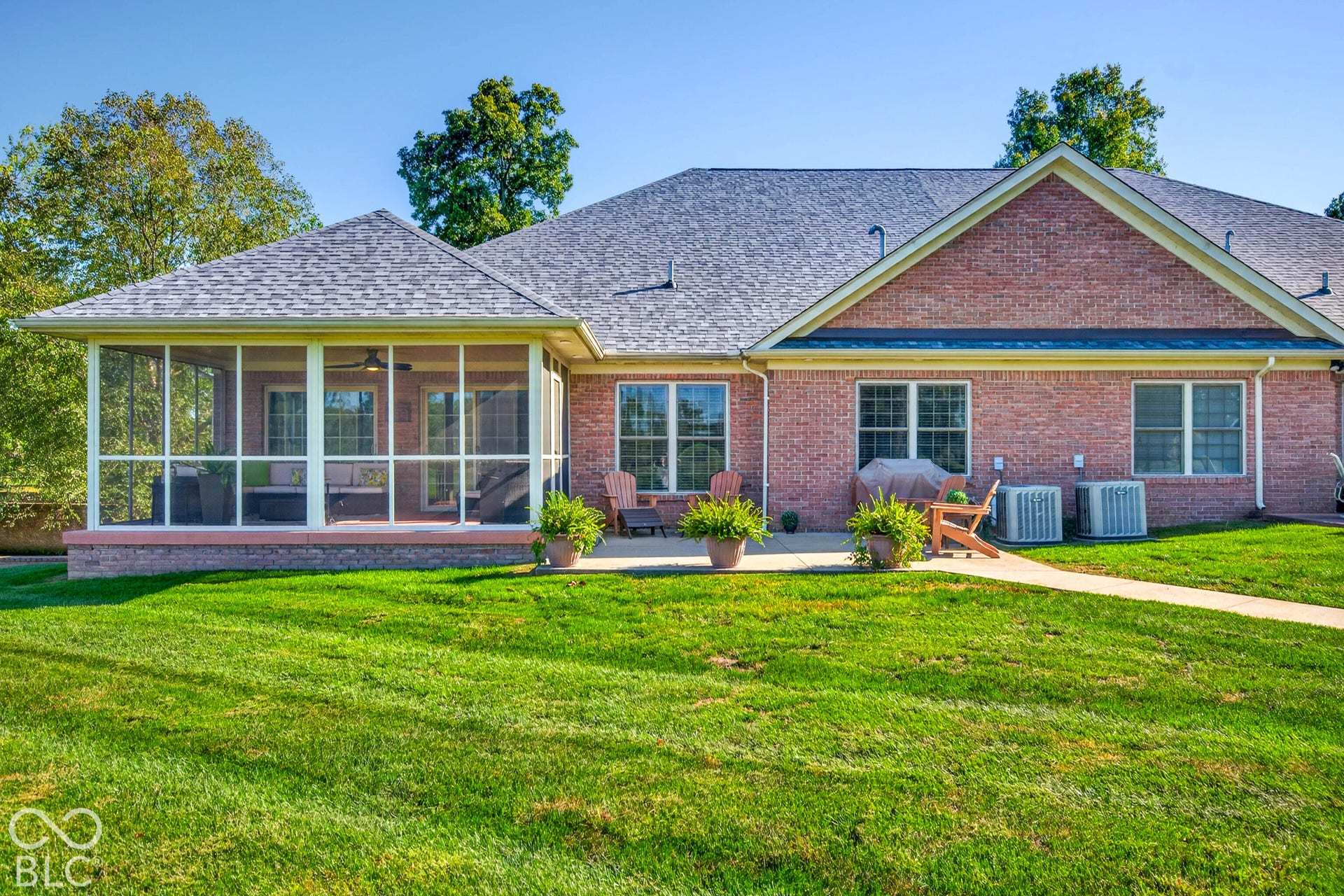 Red brick exterior with a screened-in porch, a concrete patio, and a shingled roof