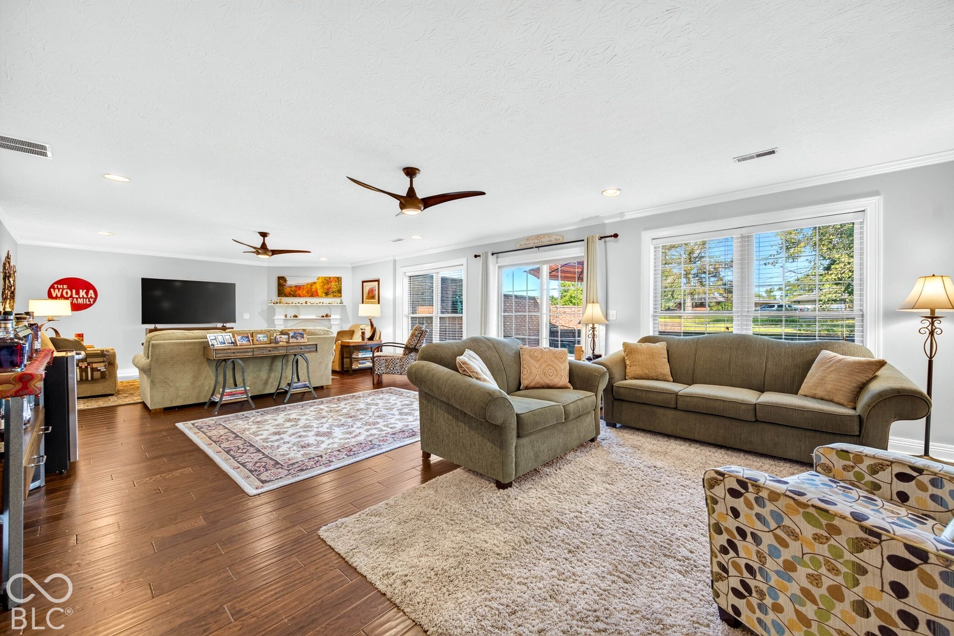 Spacious living area featuring wood-finish flooring, recessed lighting, and multiple ceiling fans