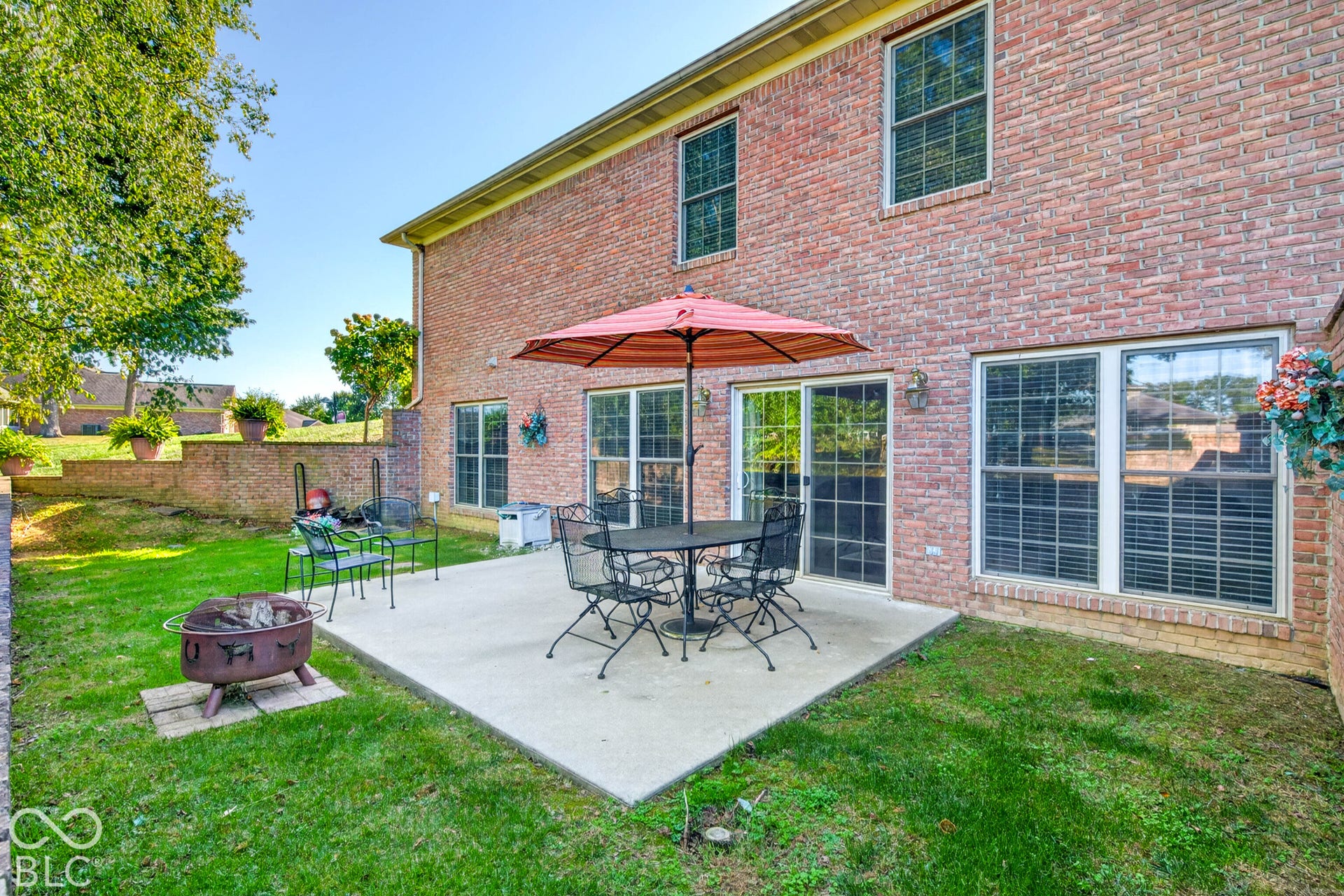 Brick exterior featuring a concrete patio, sliding glass door, and multiple windows