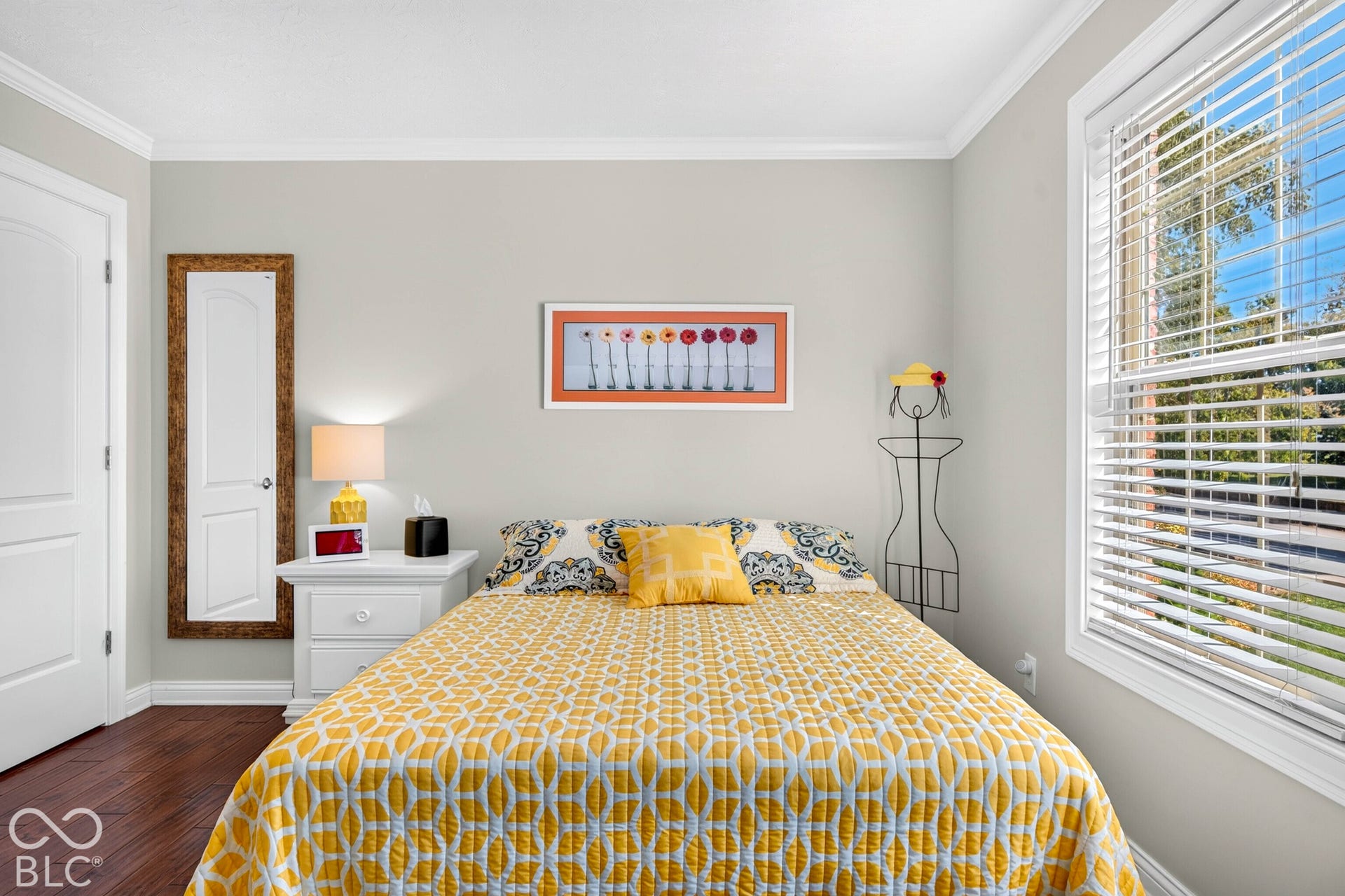 Rich wood-finish flooring, white crown molding, and a white paneled door