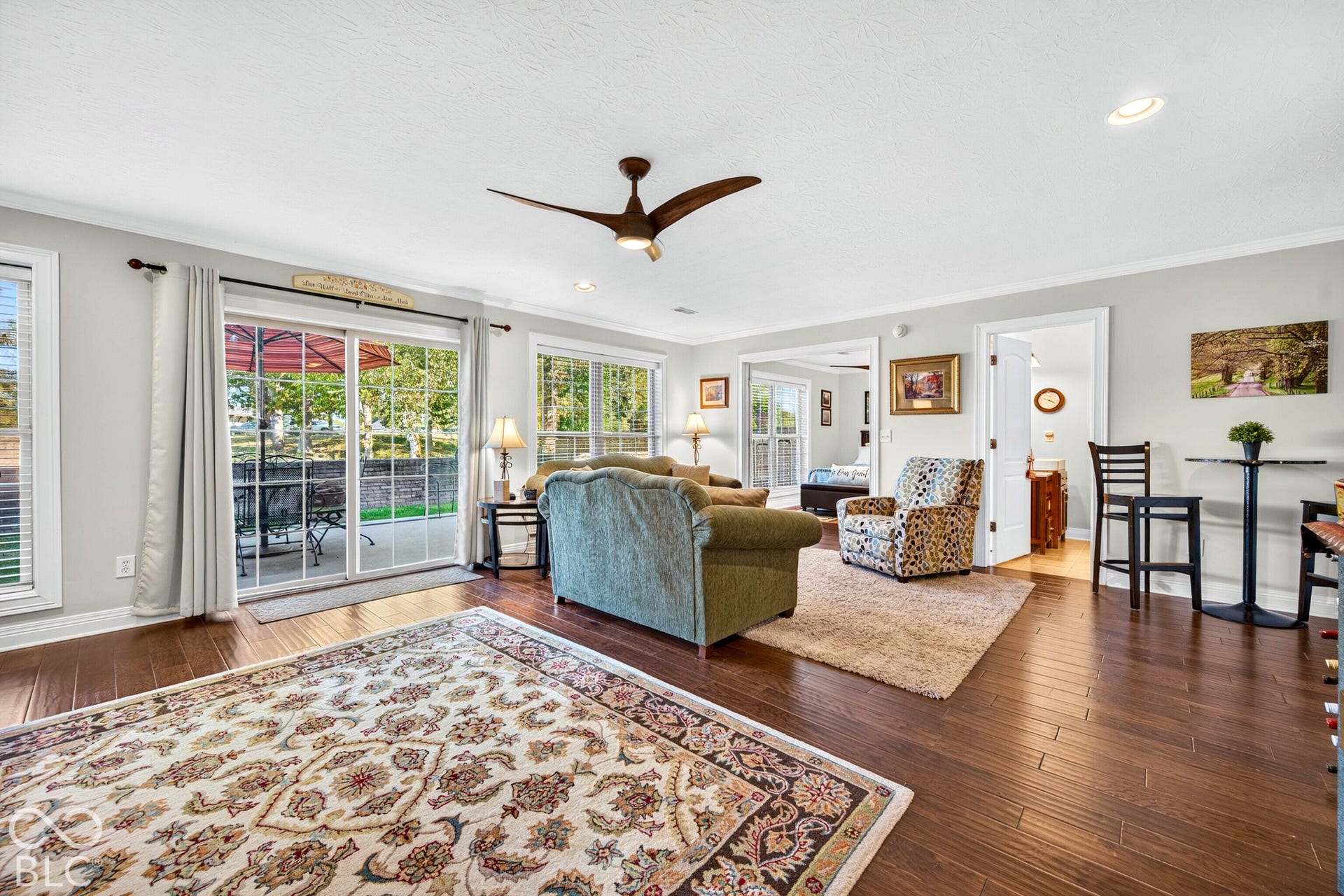 Hardwood-style flooring throughout, ceiling fan with integrated lighting, recessed lighting, and multiple windows with blinds