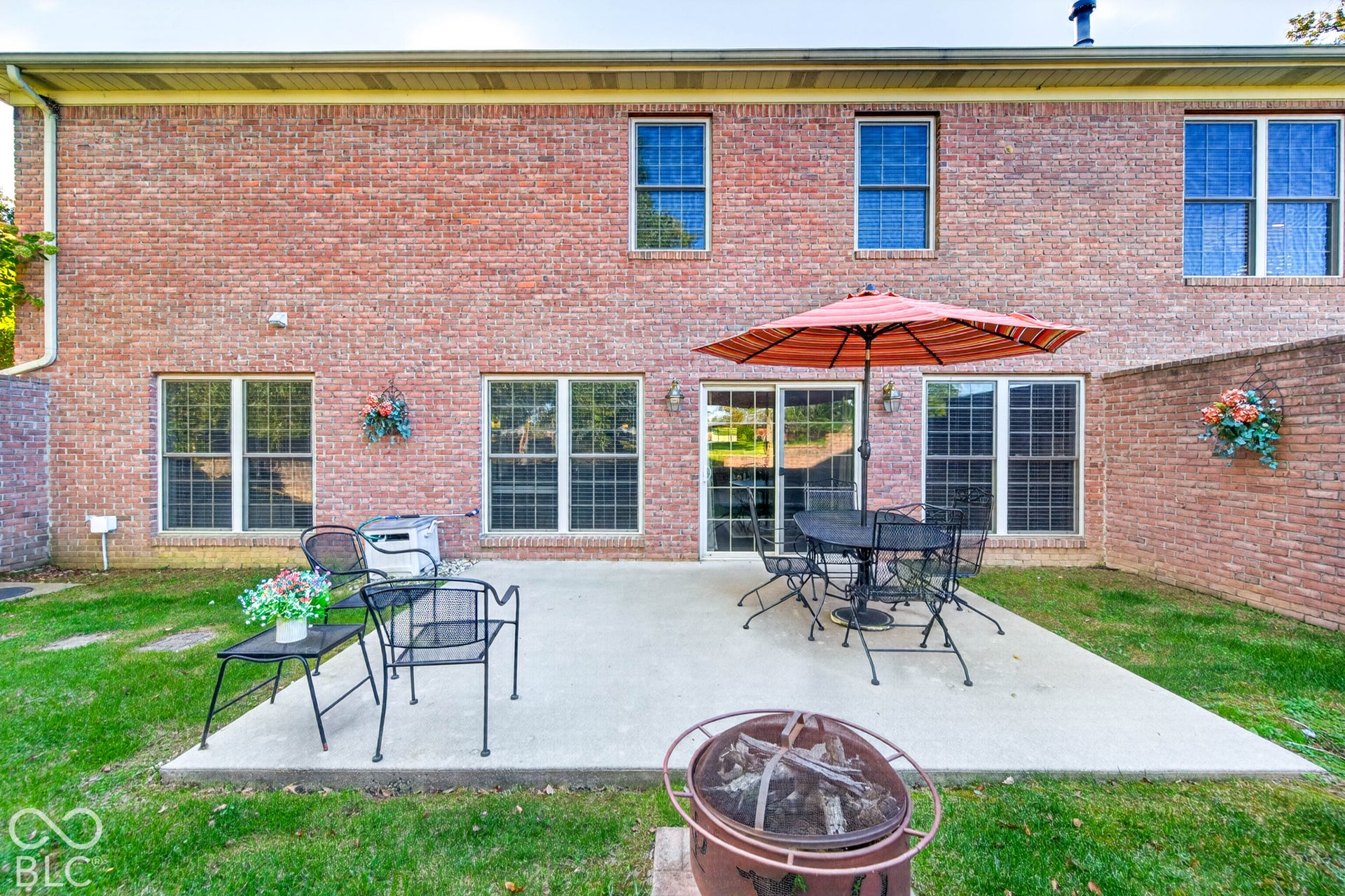 Brick exterior with multiple windows and a concrete patio