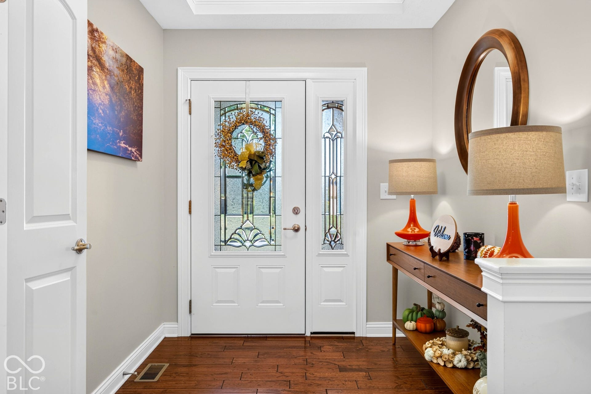 Hardwood flooring, white paneled interior doors, leaded glass entry door, matching leaded glass sidelight, and crown molding
