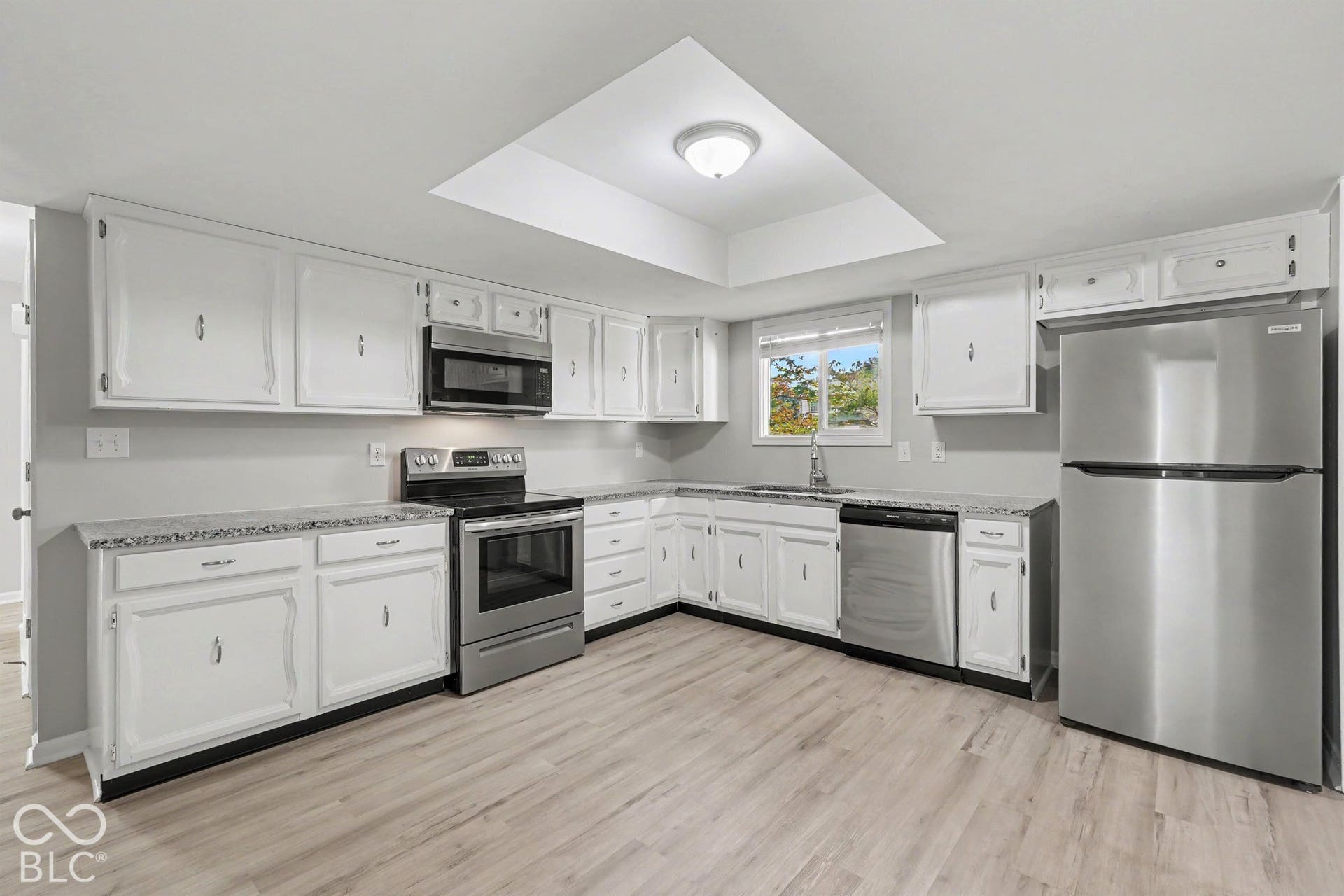 Kitchen featuring white cabinetry, wood-finish flooring, stainless steel appliances, granite-style countertops, and recessed lighting