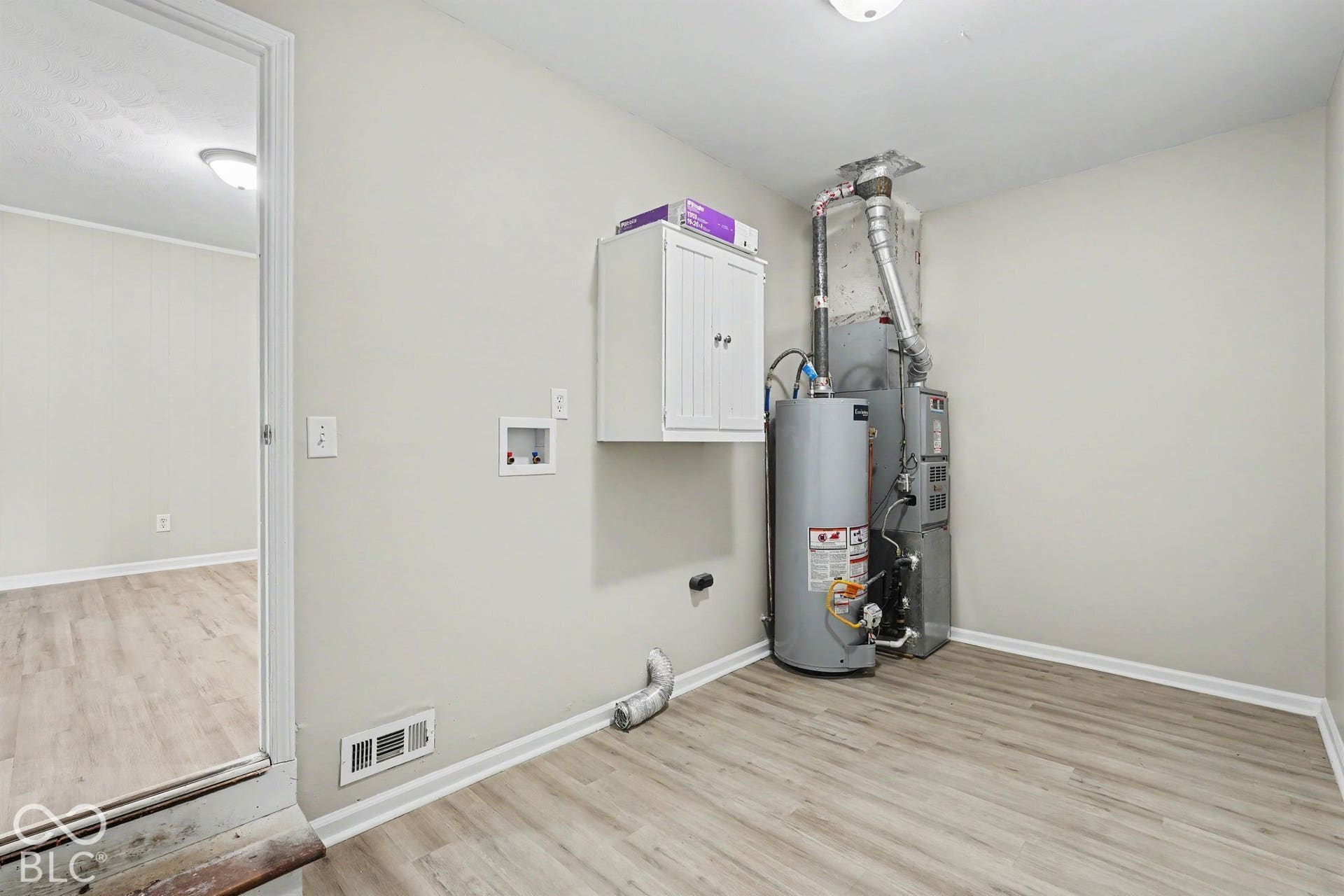 Utility area featuring a water heater, furnace, and wood-finish flooring